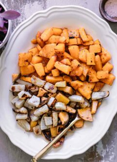 baked turnips and butternut squash on a white plate with a gold fork