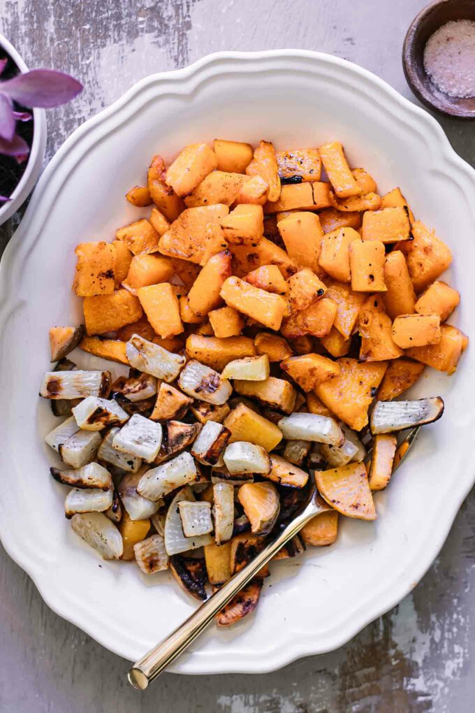 baked turnips and butternut squash on a white plate with a gold fork