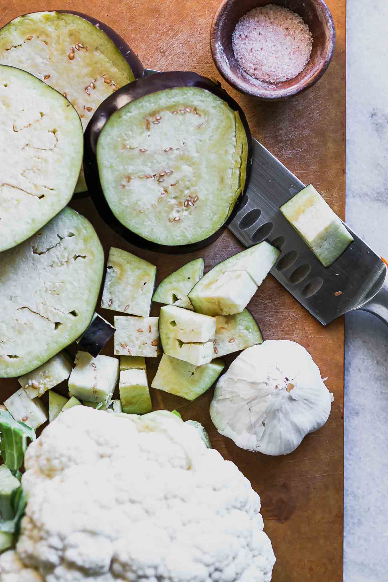 sliced eggplant and cauliflower on a wood cutting board