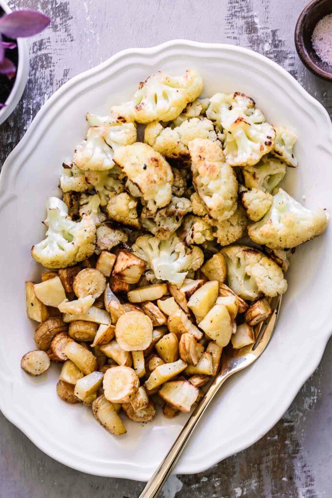 baked parsnips and cauliflower on a white plate with a gold fork