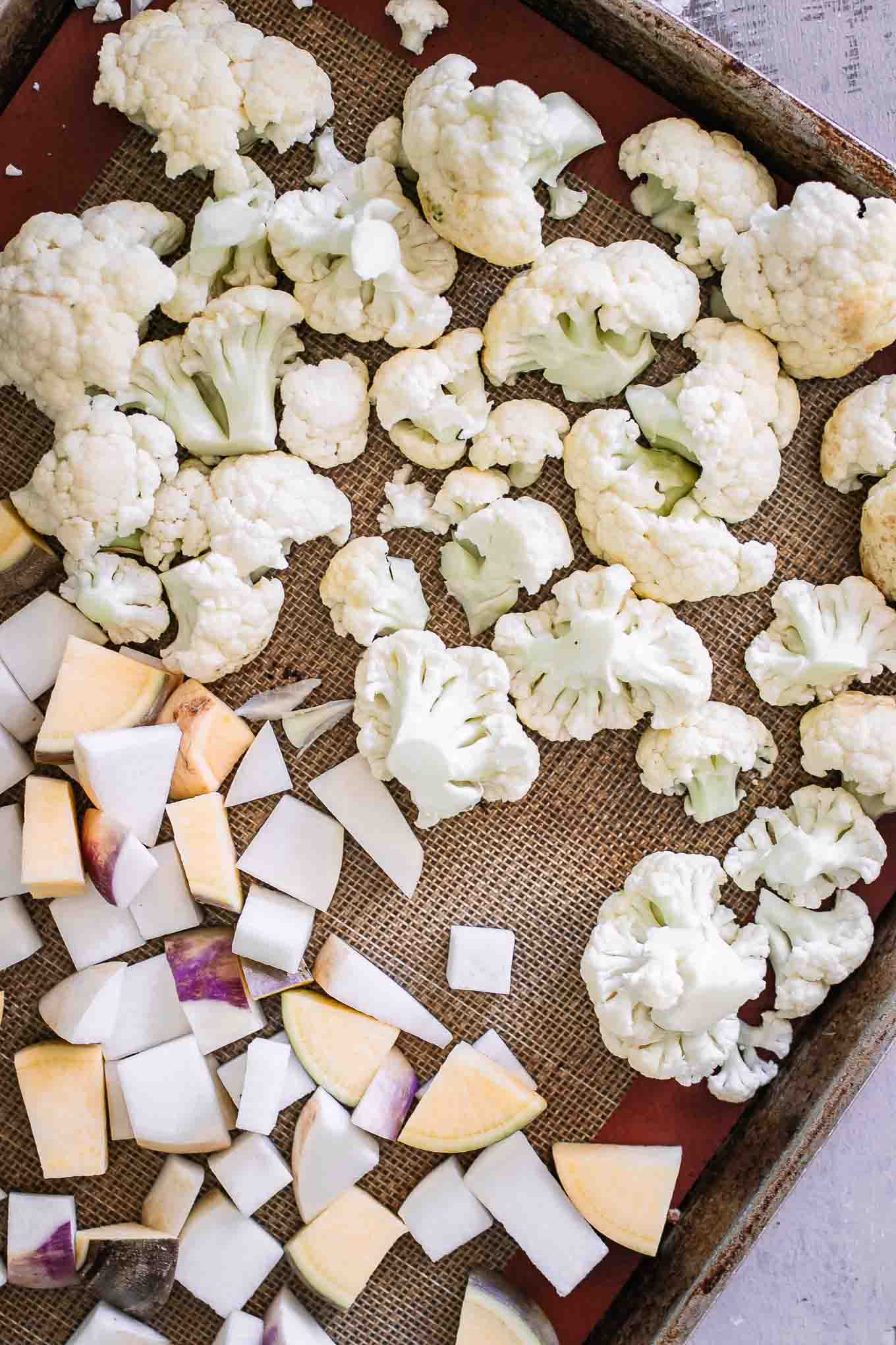 cut cauliflower and turnips on a baking sheet before roasting