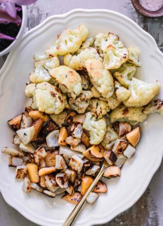 roasted cauliflower and turnips on a white plate with a gold fork