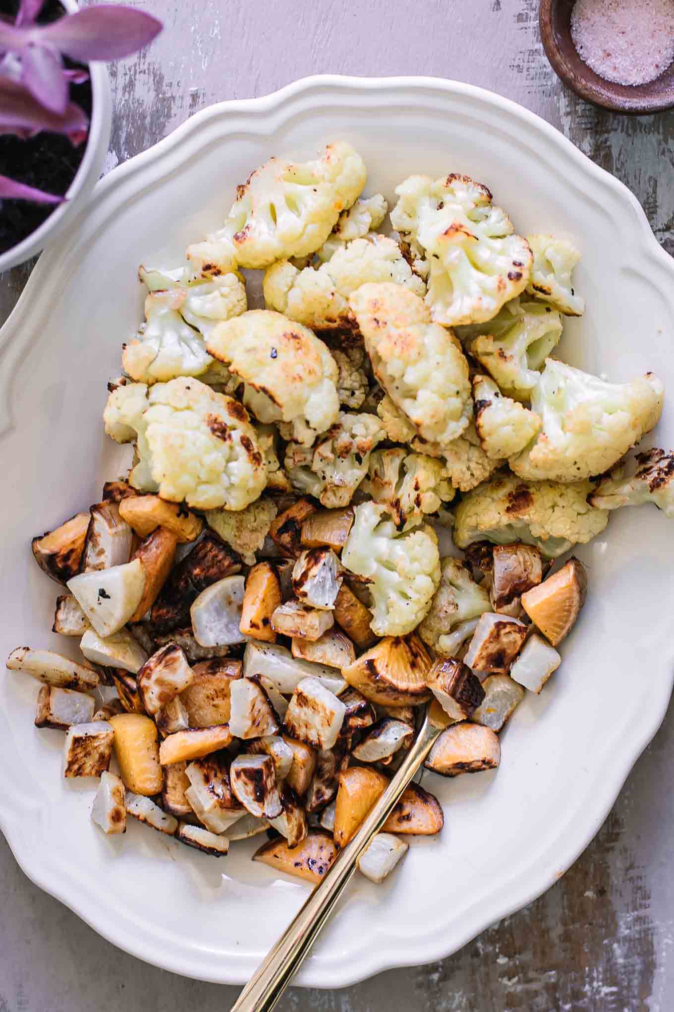 roasted cauliflower and turnips on a white plate with a gold fork