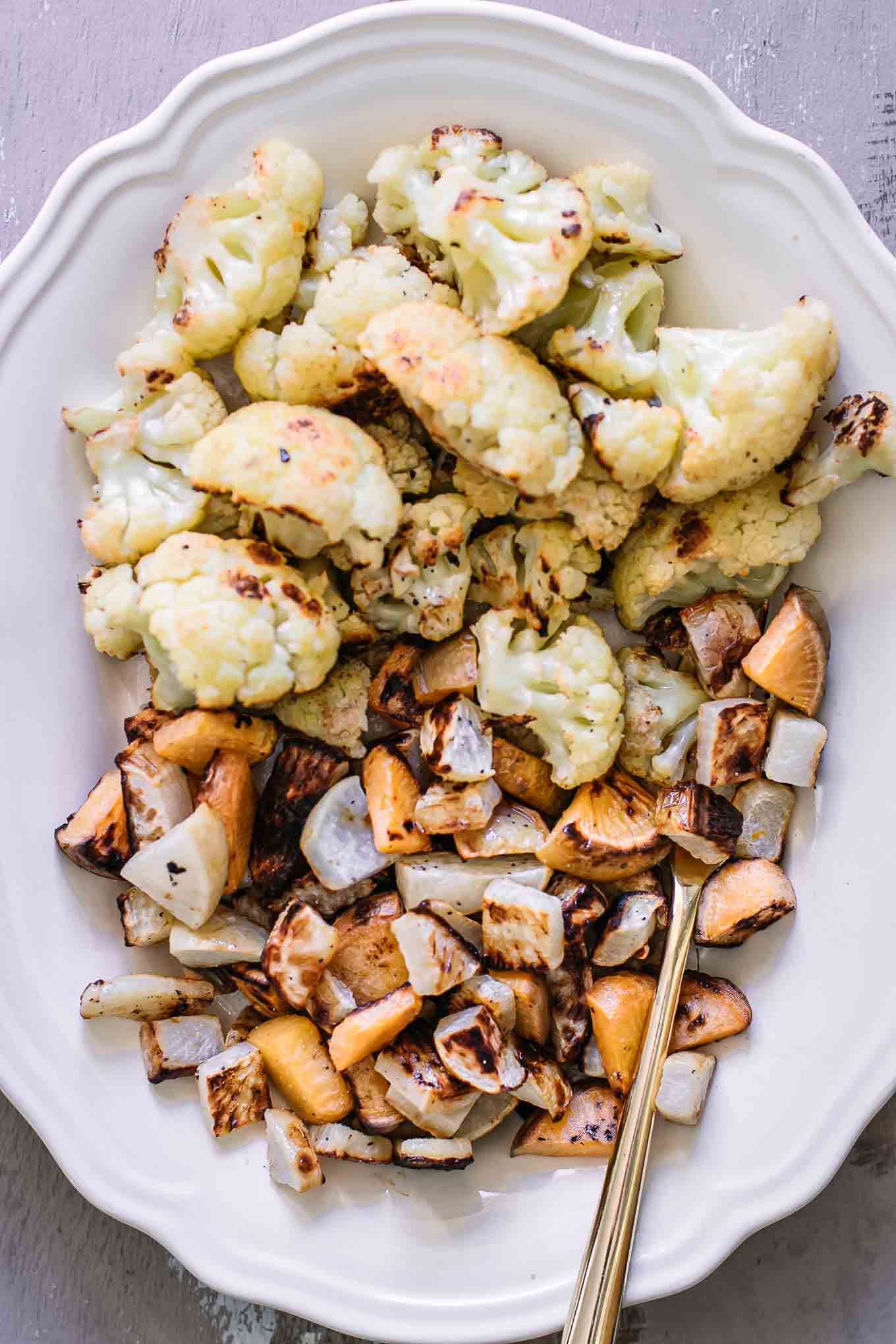 a close up photo of roasted turnips and cauliflower on a white plate