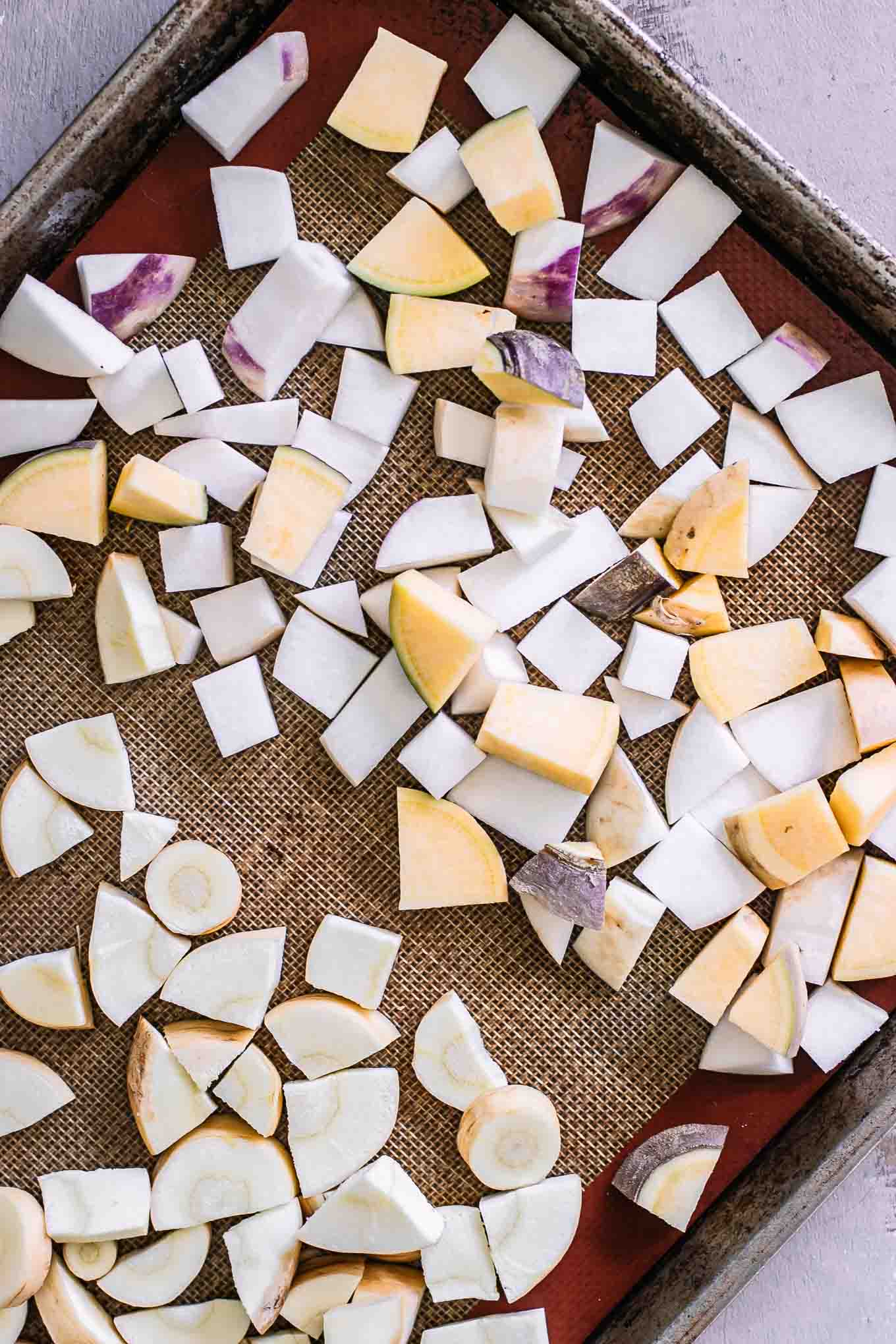 cut parsnips and turnips on a baking sheet before roasting