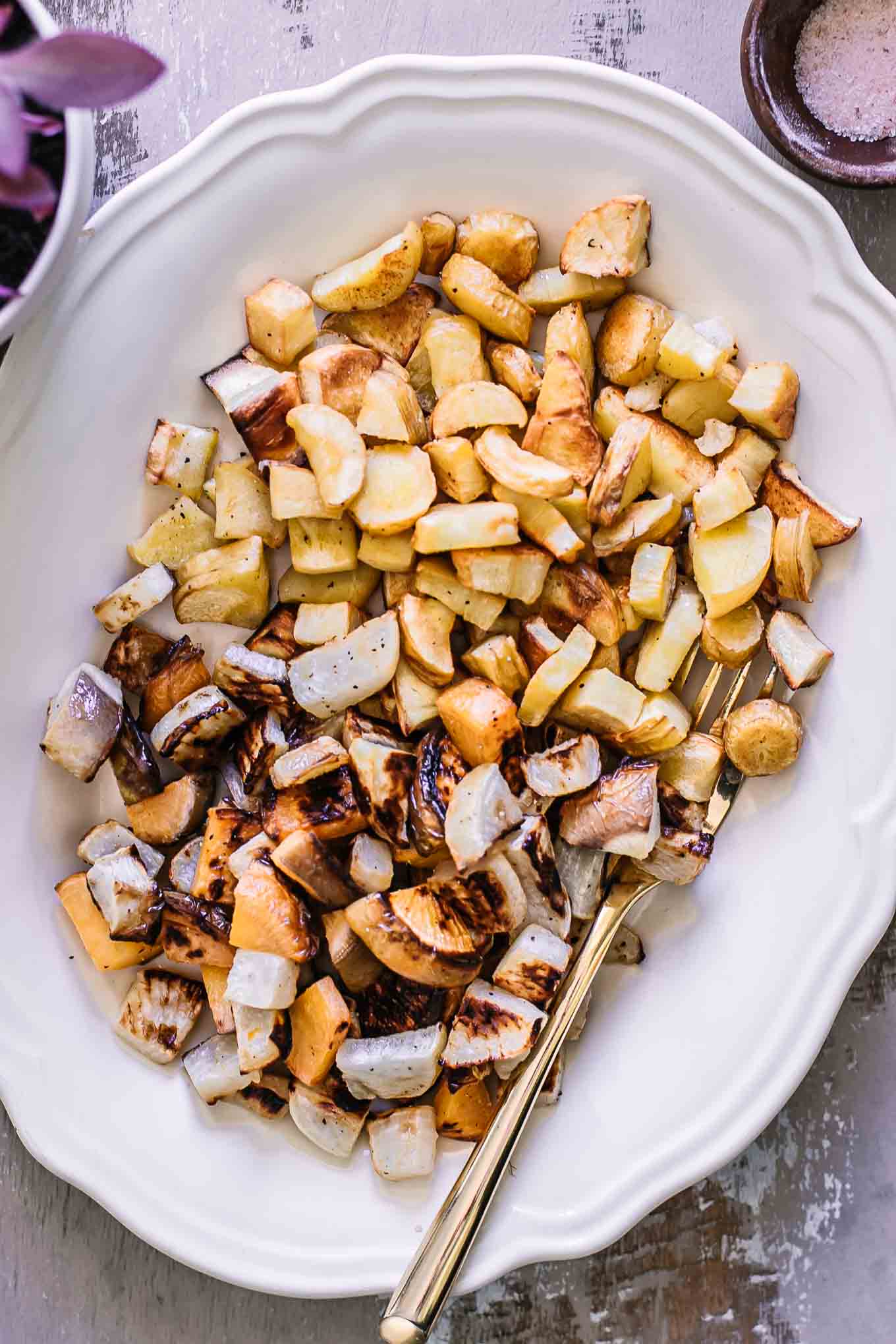 roasted parsnips and turnips on a white plate with a gold fork