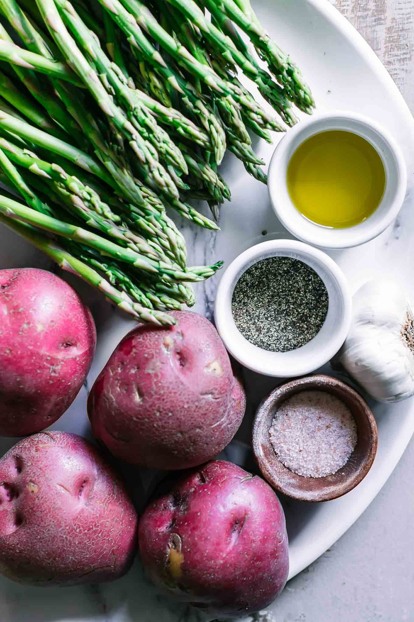 asparagus potatoes, garlic, oil, salt, and pepper on a white table