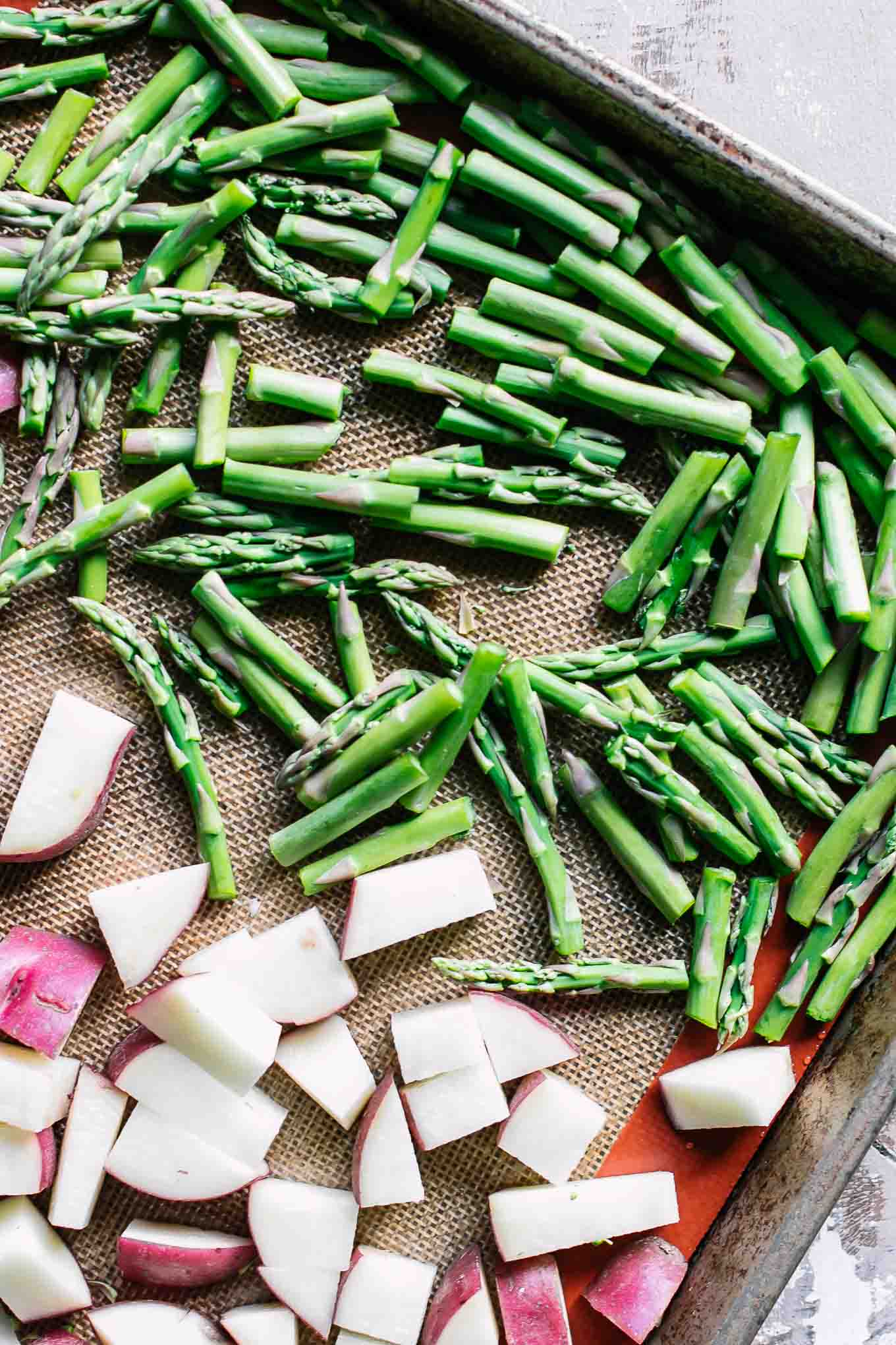 cut asparagus and potatoes on a baking sheet before roasting