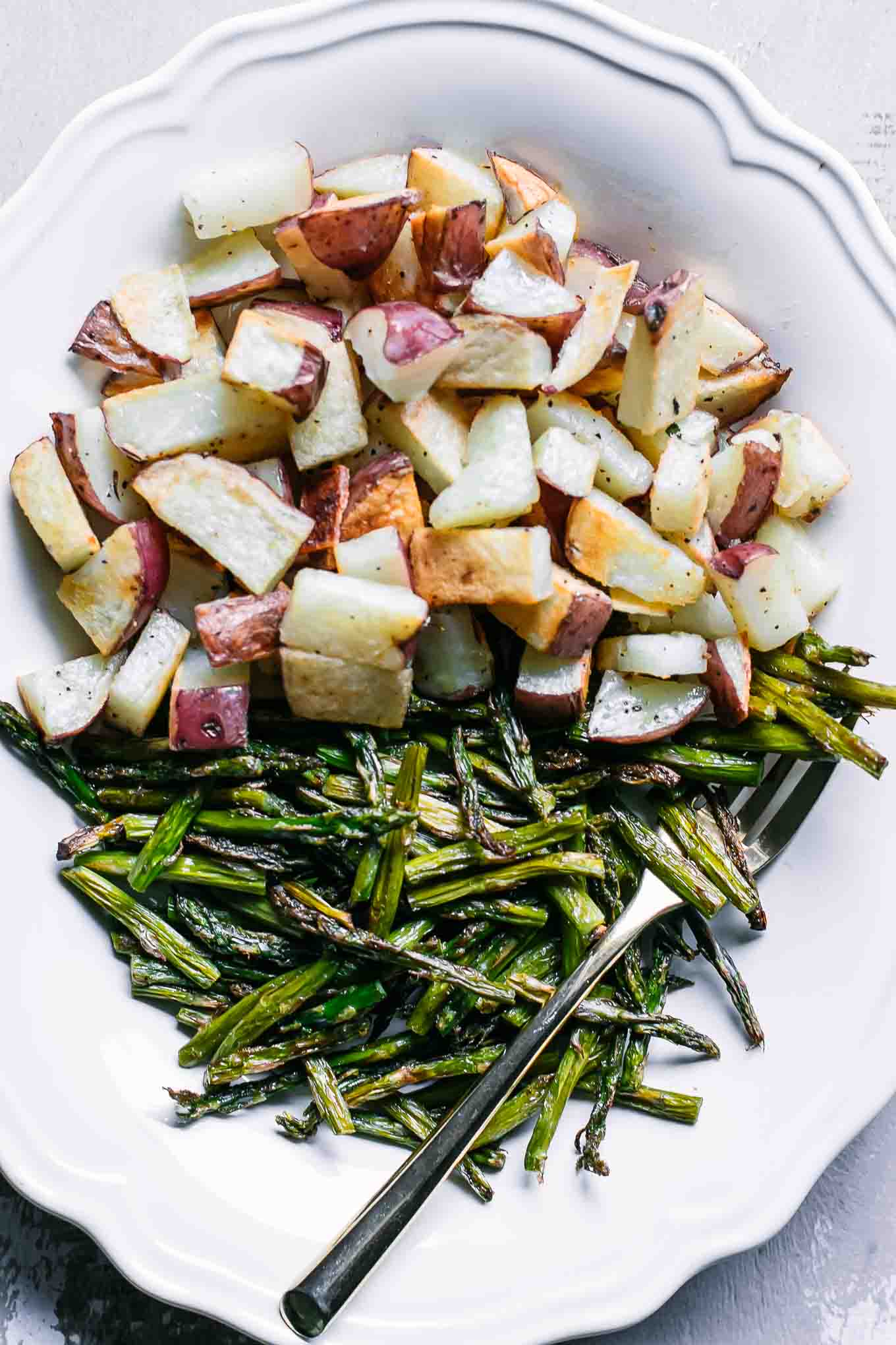 a close up photo of roasted potatoes and baked asparagus