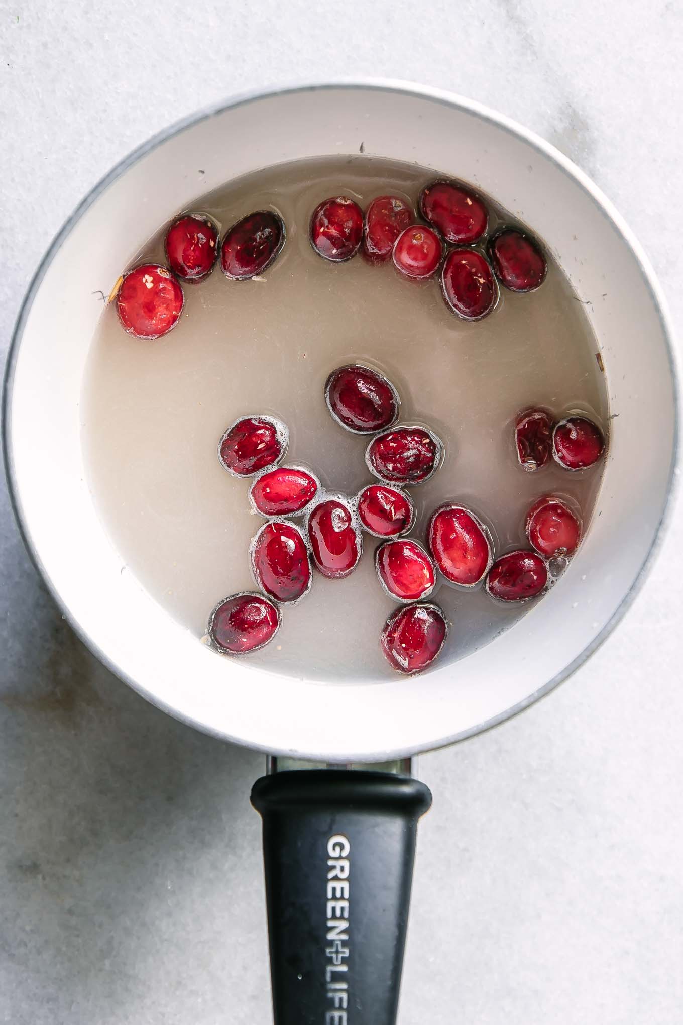 a small sauce pan with oatmeal, cranberries, and water before cooking