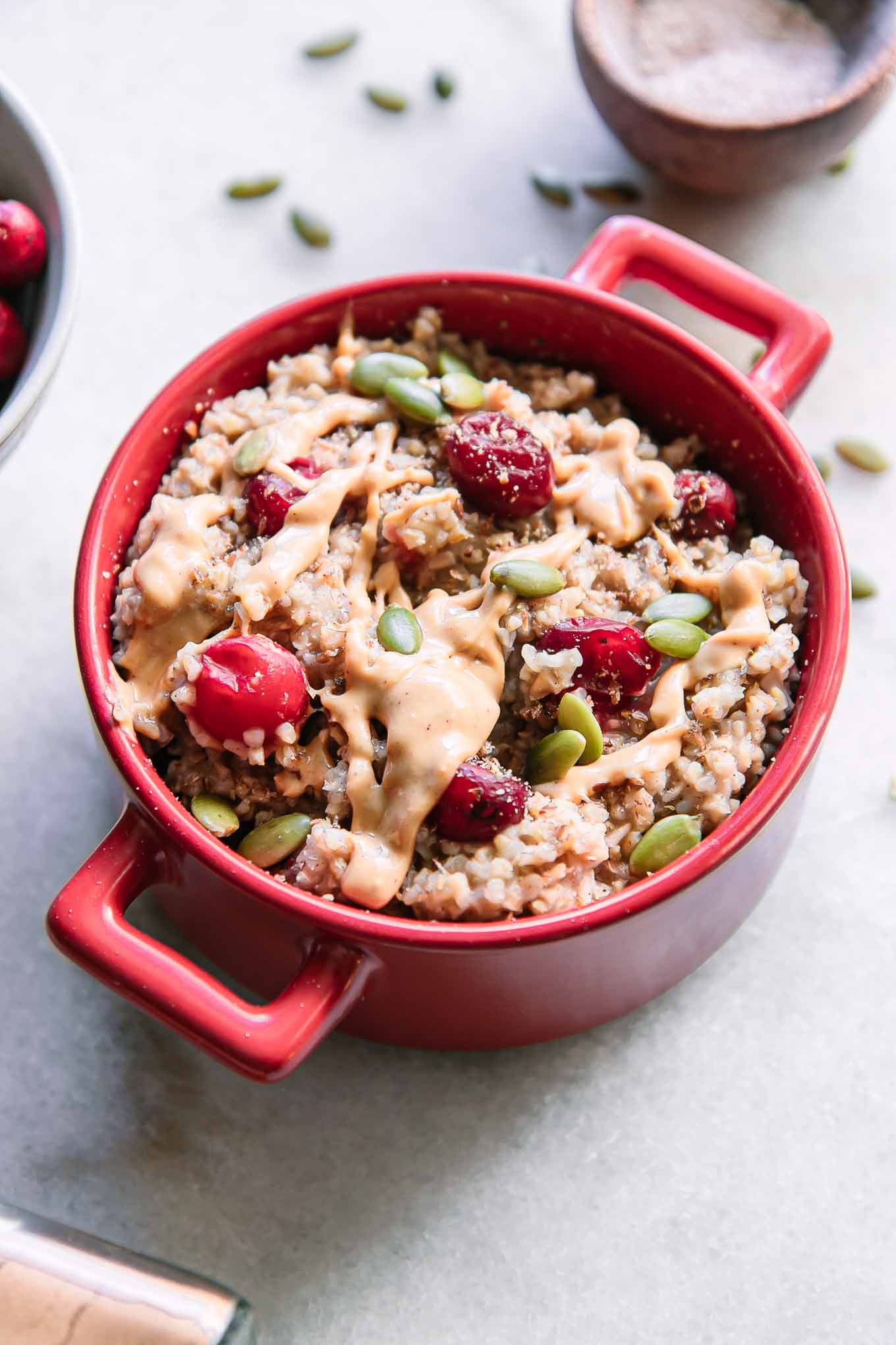 a red bowl with cranberry oatmeal and peanut butter drizzled on top