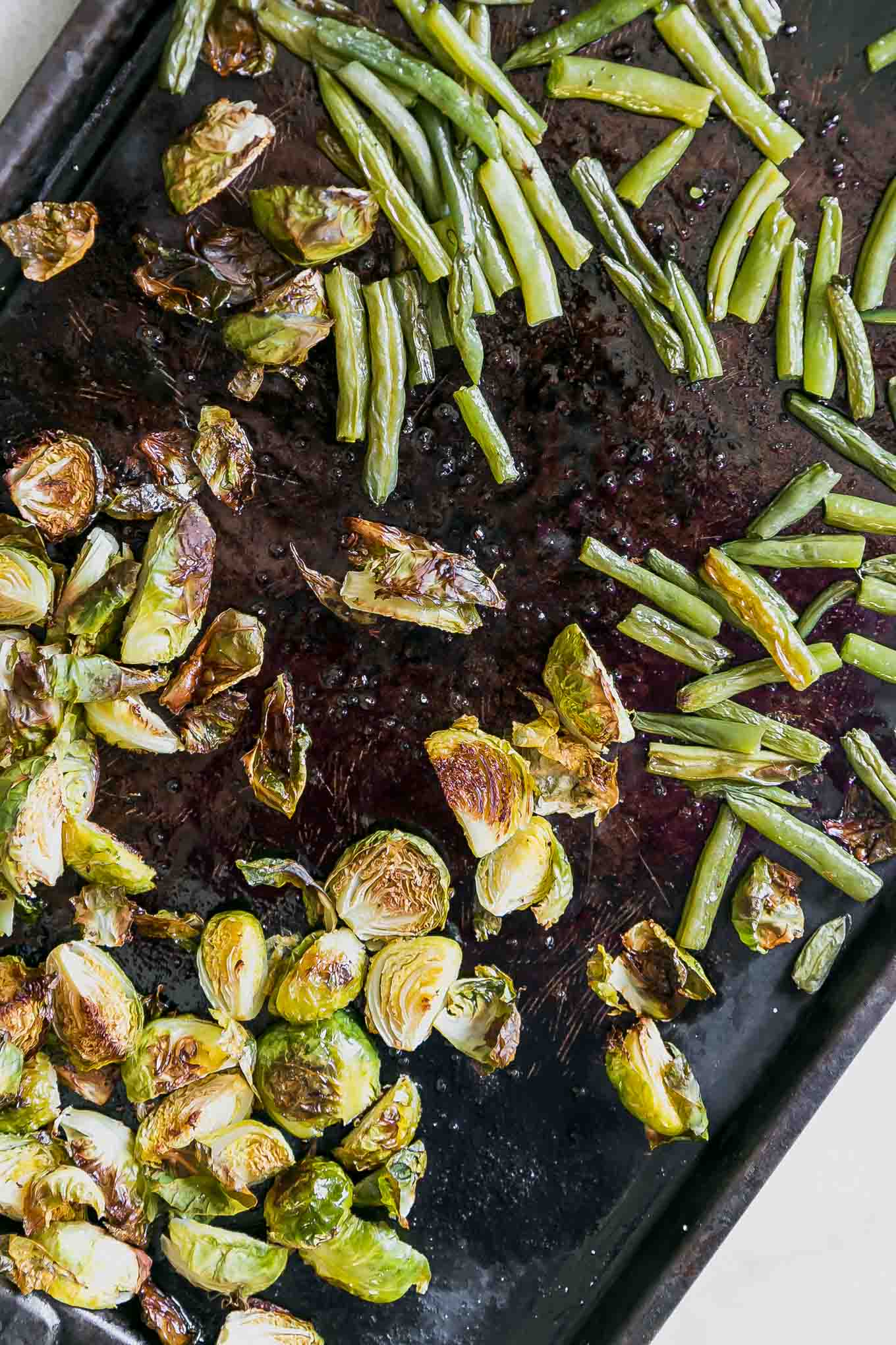 green beans and brussels sprouts on a roasting pan after baking