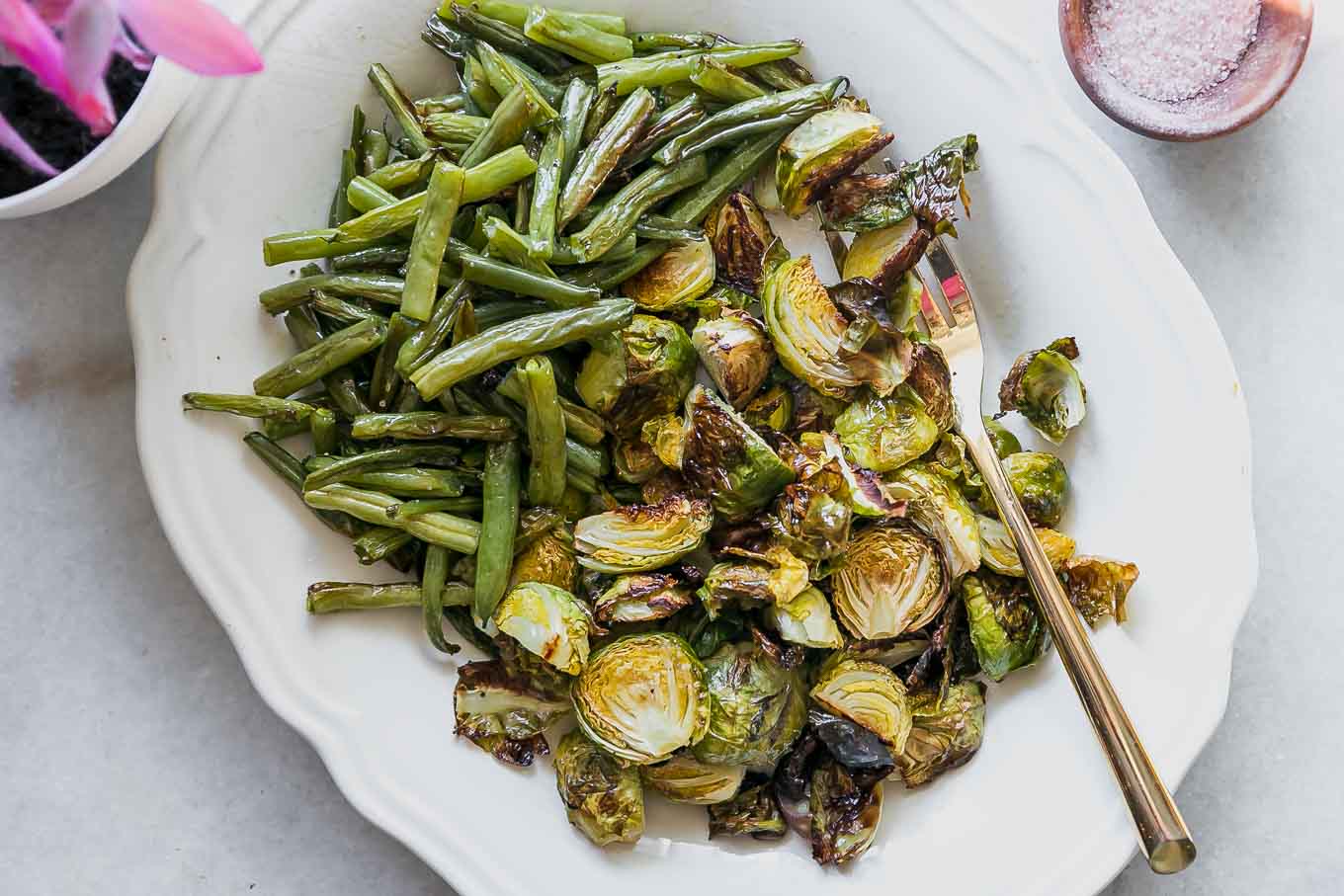 baked green beans and brussels sprouts on a white side dish