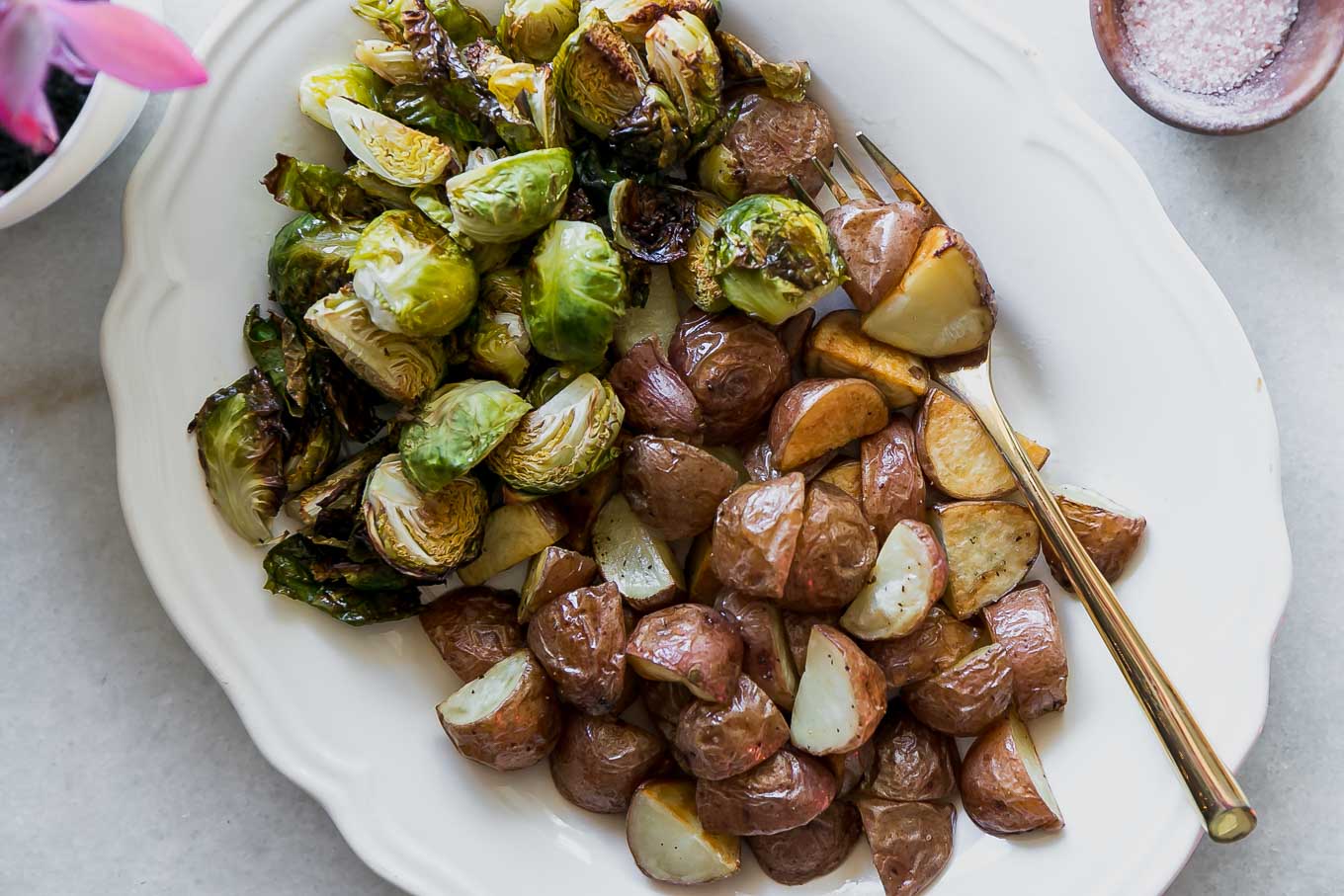 roasted potatoes and brussels sprouts on a white side dish