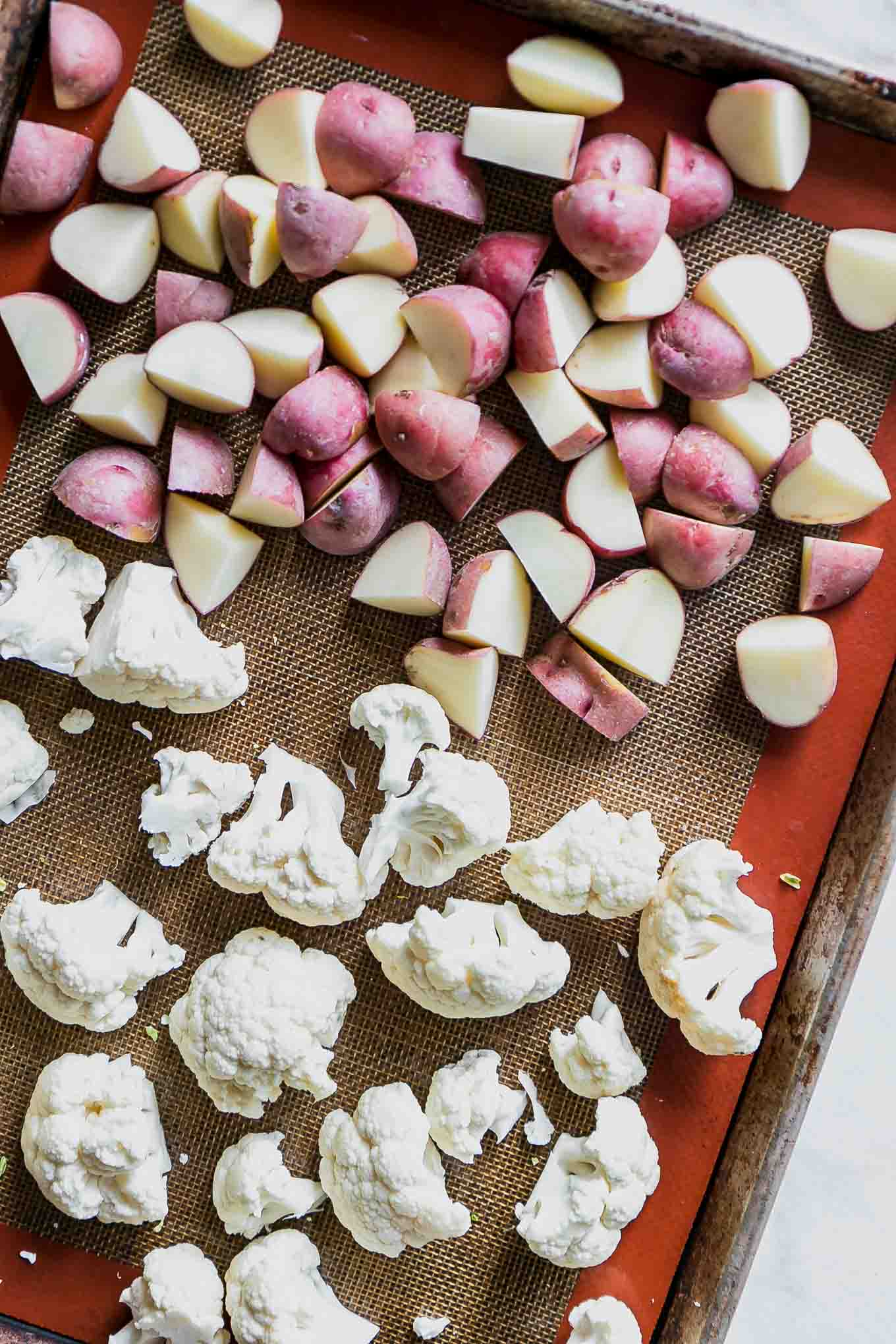 cut cauliflower and potatoes on a baking sheet before roasting