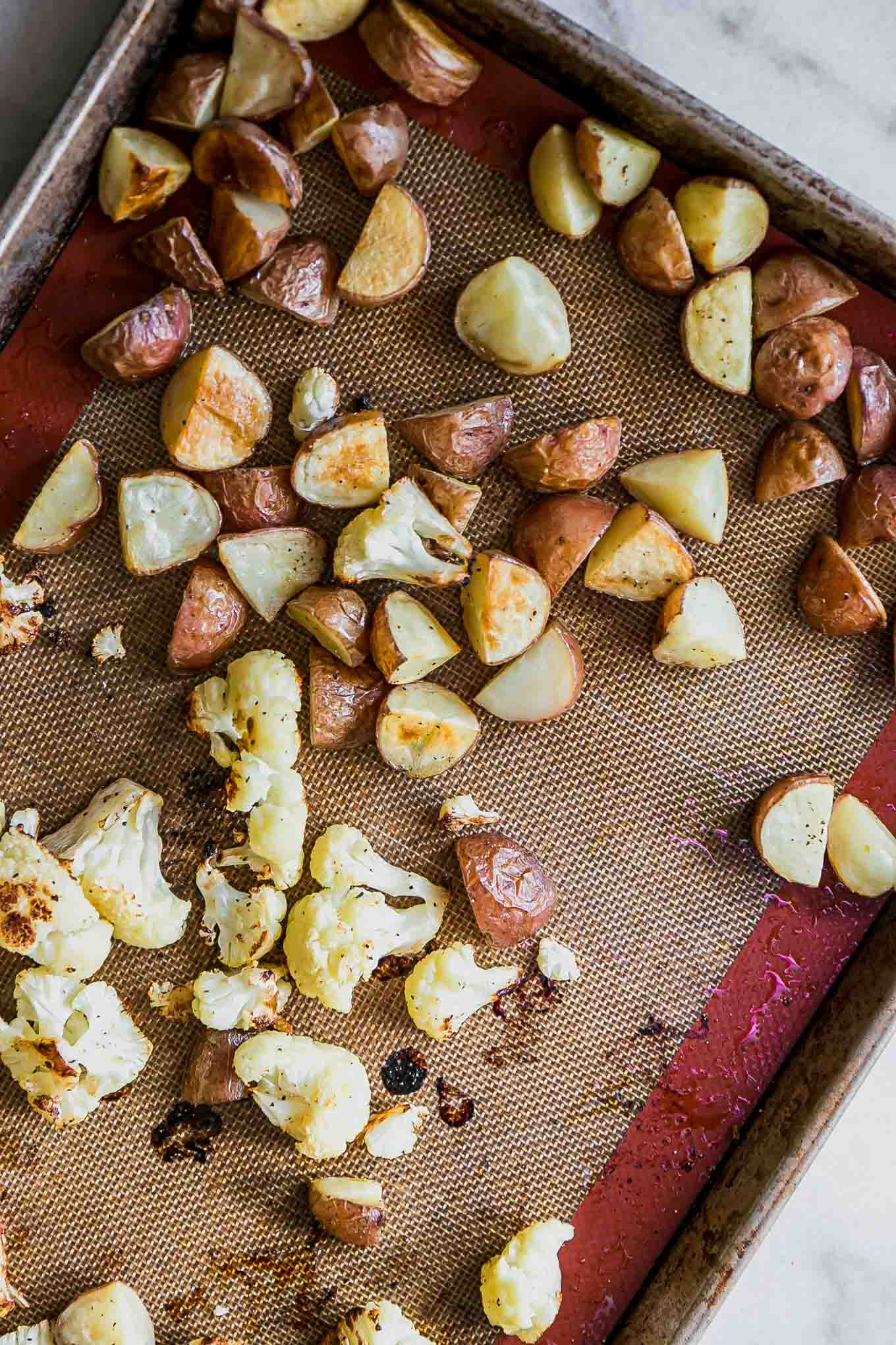 roasted potatoes and cauliflower on a baking sheet after roasting