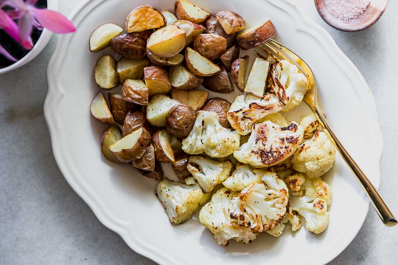 a side dish of cauliflower and potatoes on a white table