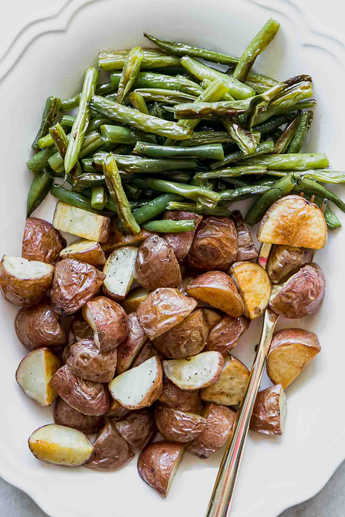 a close up photo of potatoes and green beans on a white plate