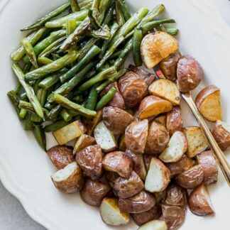 roasted green beans and potatoes on a white side plate