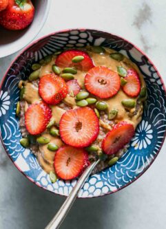 a bowl of oatmeal with strawberries and a gold fork