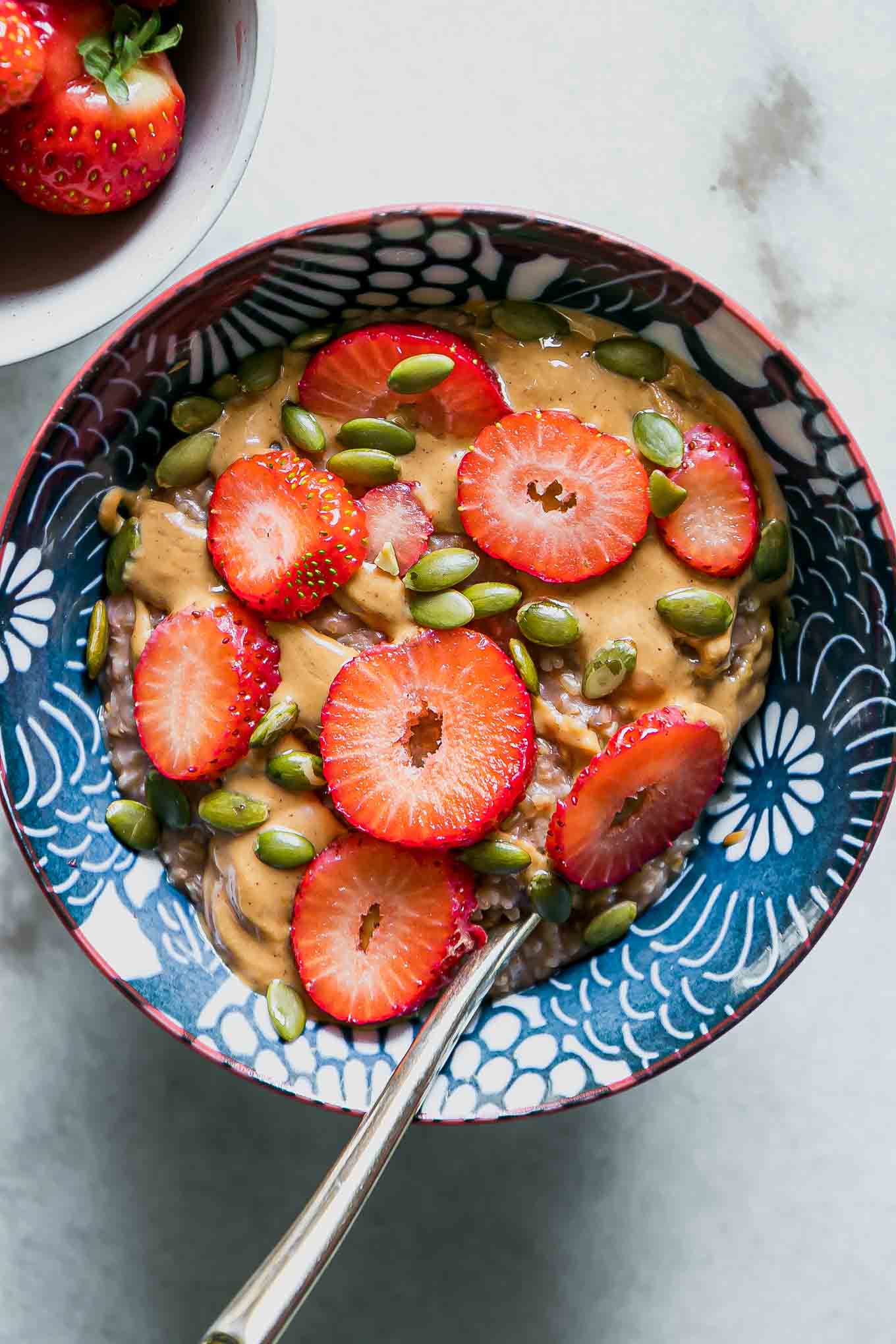 a bowl of oatmeal with strawberries and a gold fork