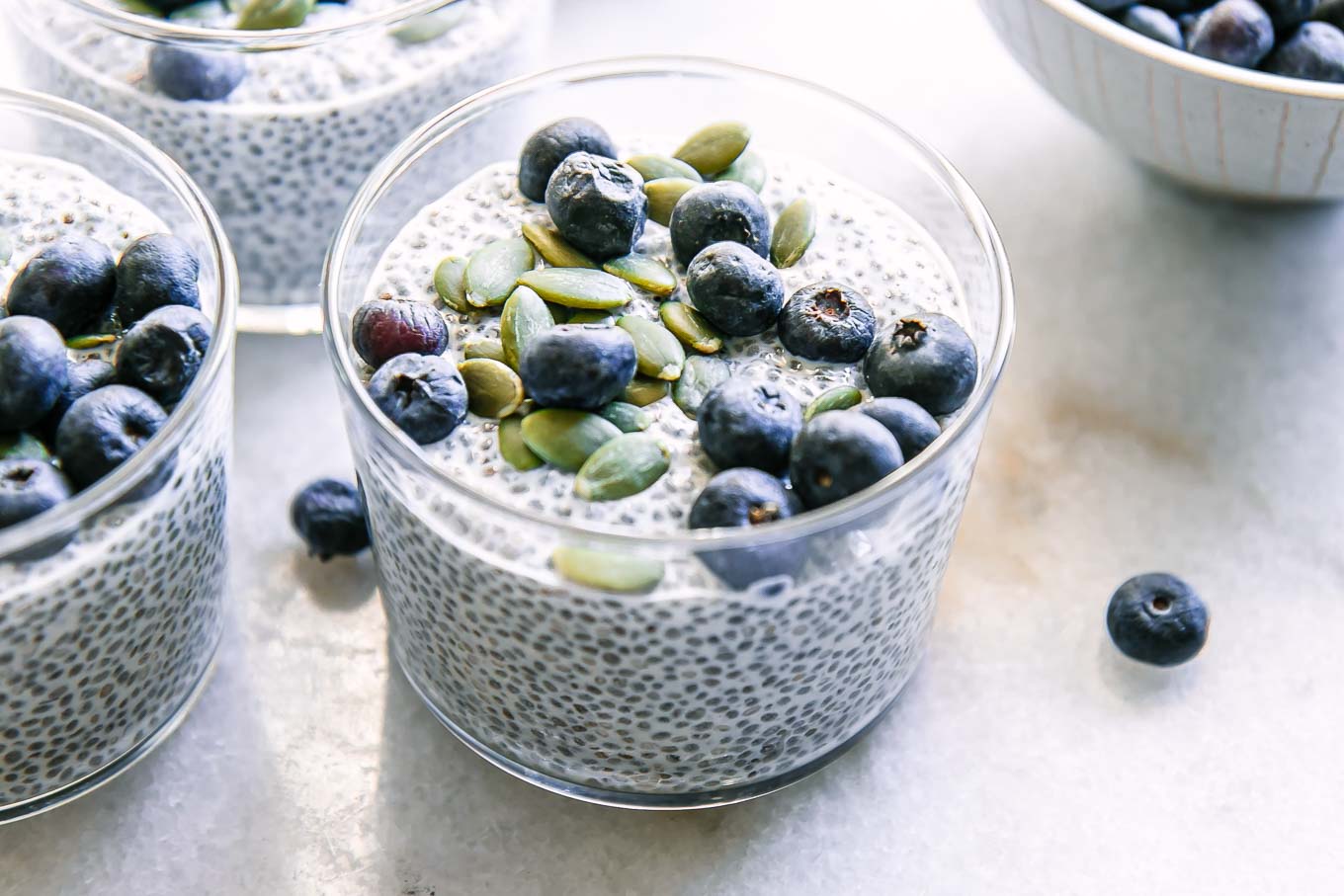 a jar of chia seed pudding with blueberries on a white countertop