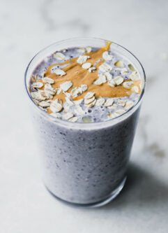 a blueberry and oatmeal smoothie in a glass with oatmeal garnish