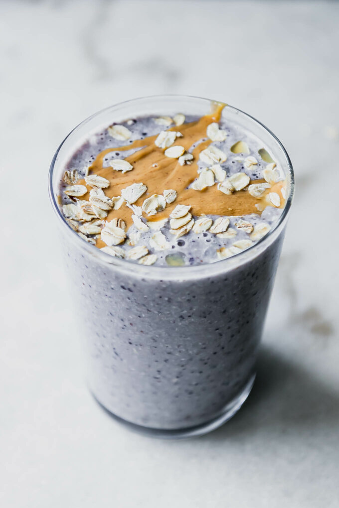 a blueberry and oatmeal smoothie in a glass with oatmeal garnish