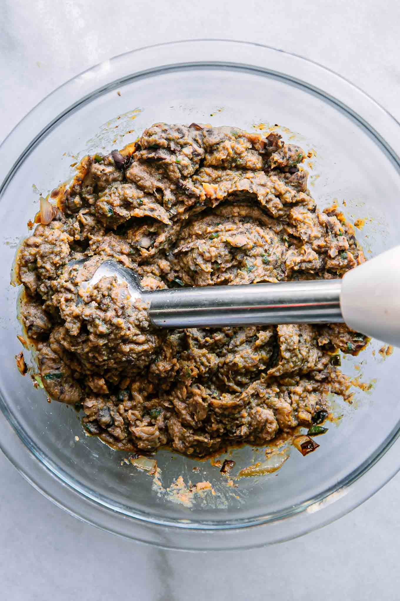 black bean and butternut squash blended in a bowl with an immersion blender on a white table