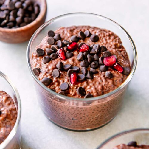 small jars of chocolate chia pudding with chocolate chips on a white table