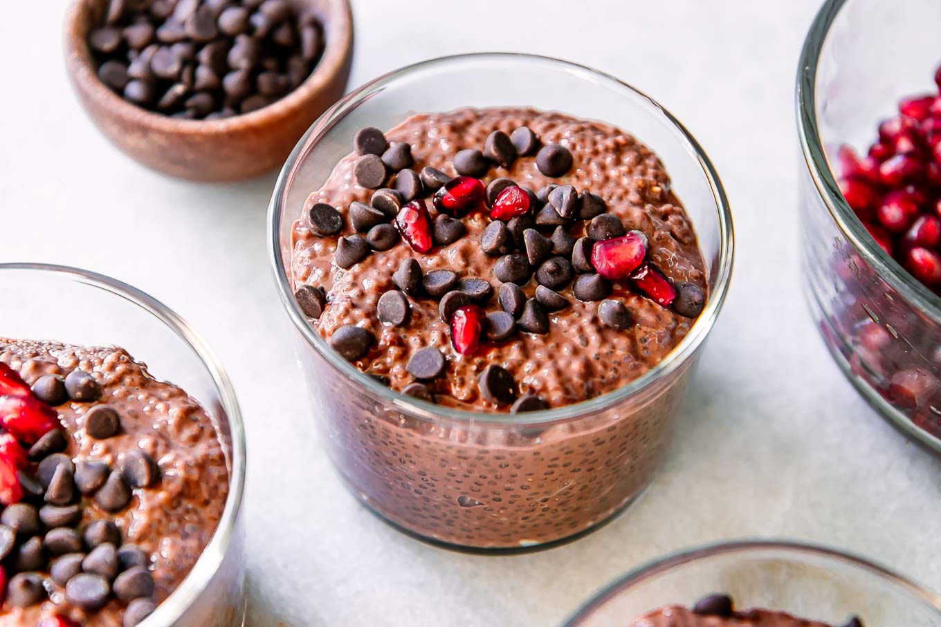 small jars of chocolate chia pudding with chocolate chips on a white table
