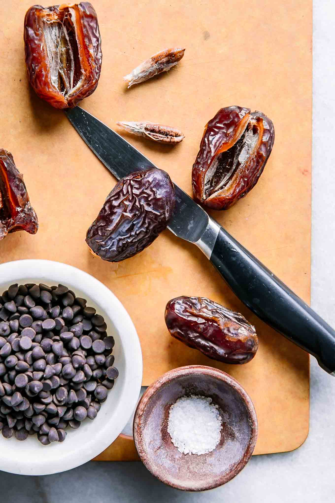 dates with seeds removed on a wood cutting board with a knife