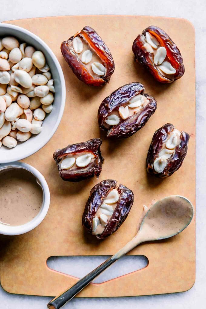 dates stuffed with peanuts and peanut butter on a wood cutting board