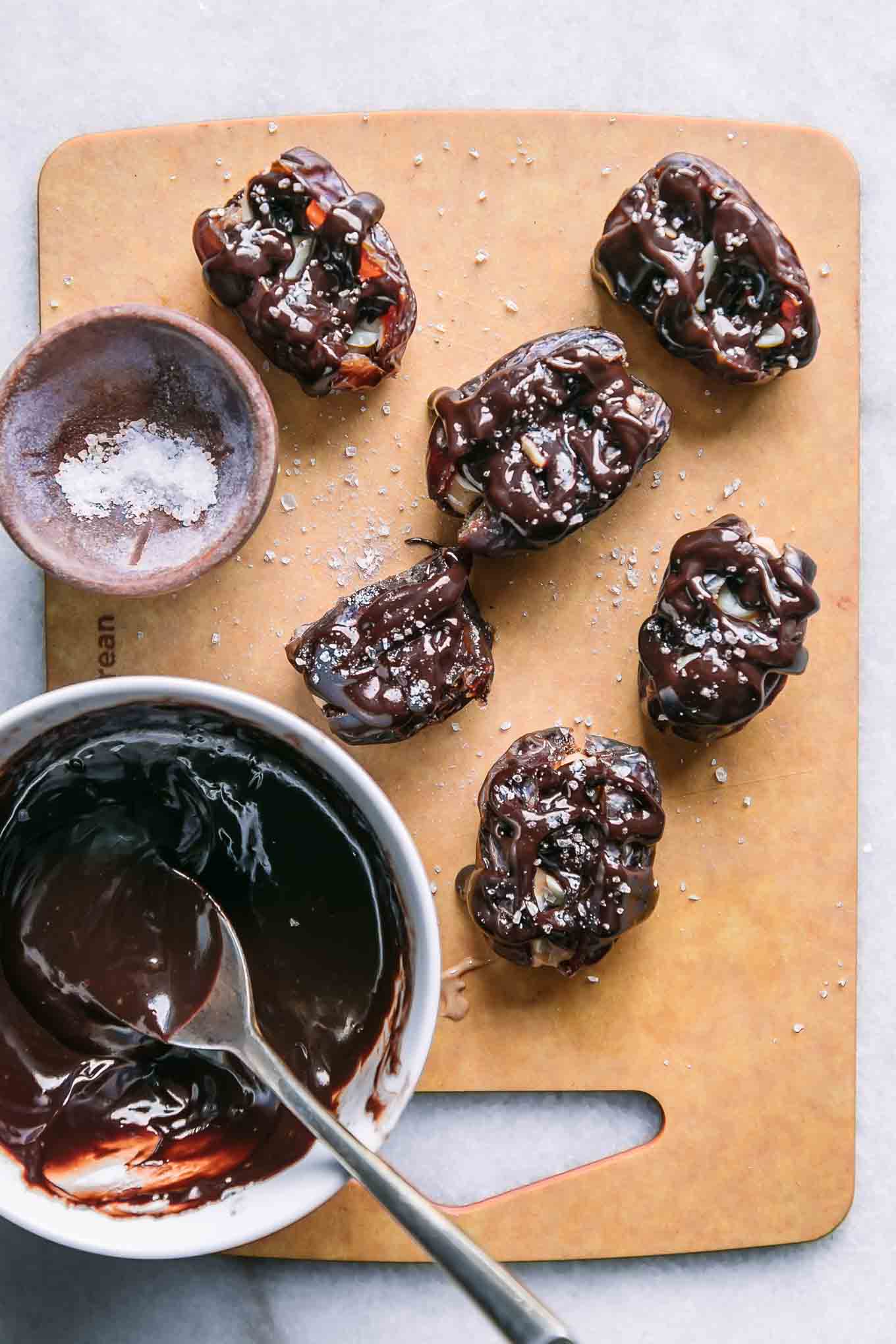 dates stuffed with peanut butter and drizzled with melted chocolate on a wood cutting board