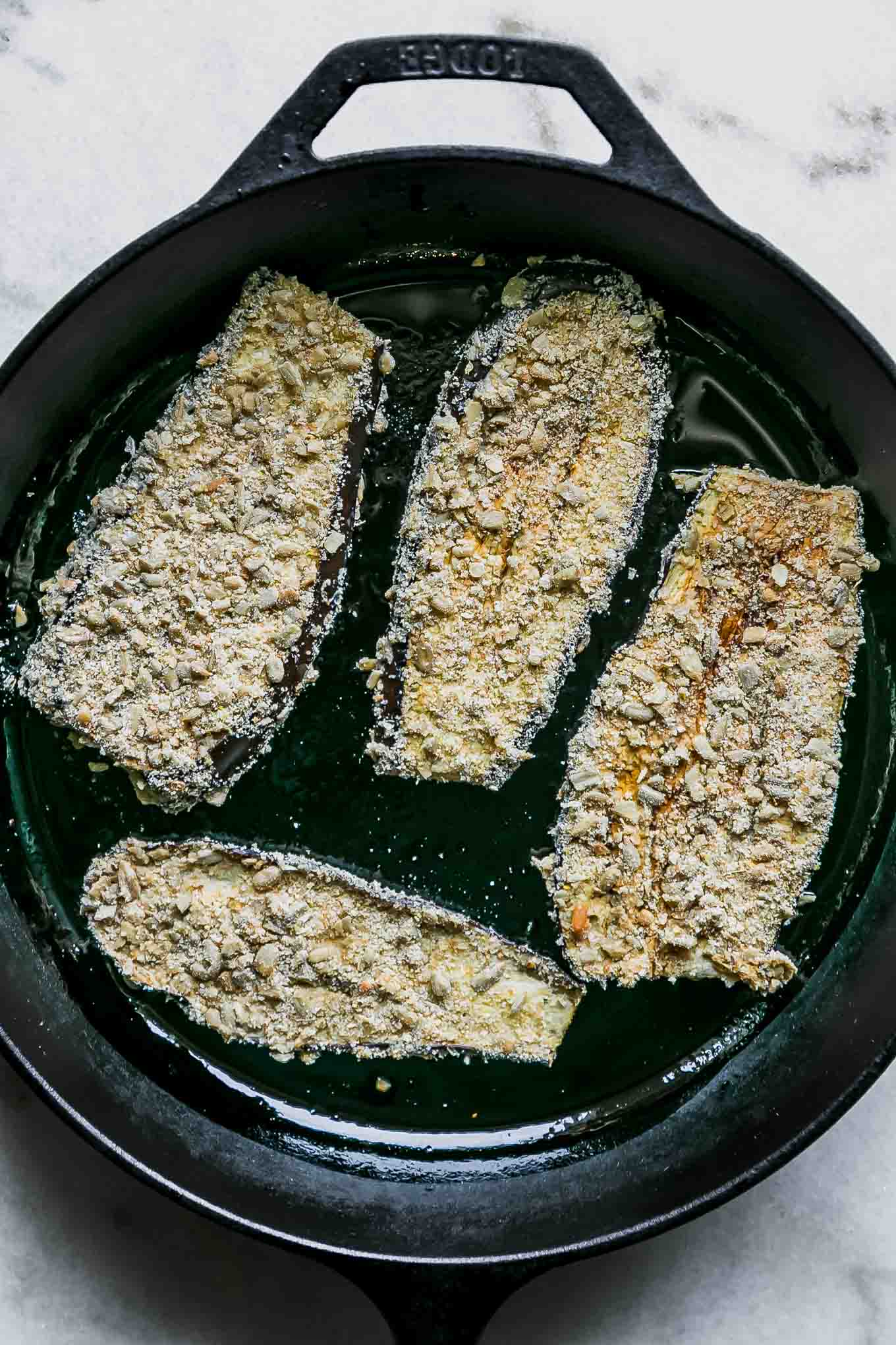 breaded eggplant slices in a cast iron skillet