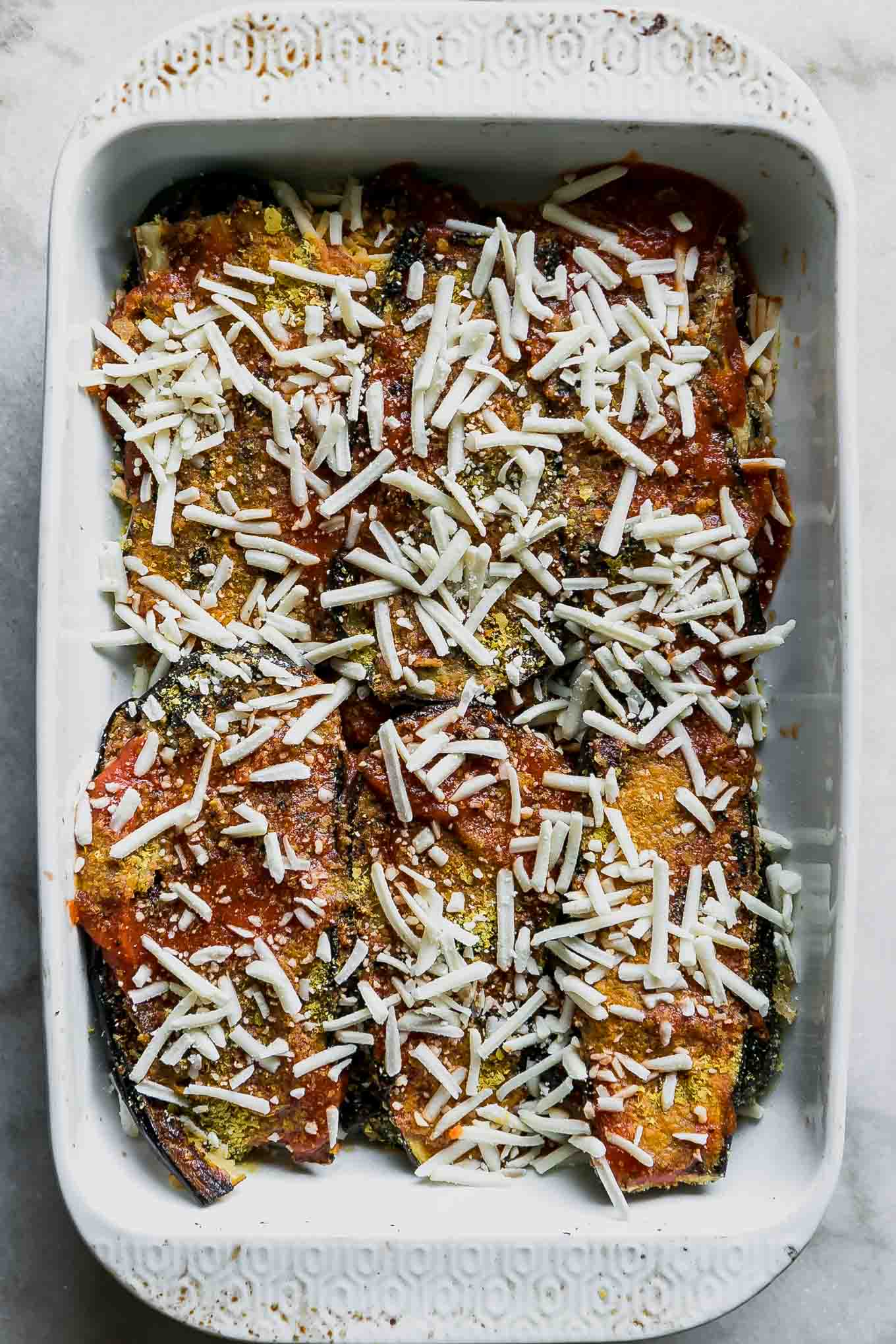 eggplant parmesan ingredients in a baking dish before cooking