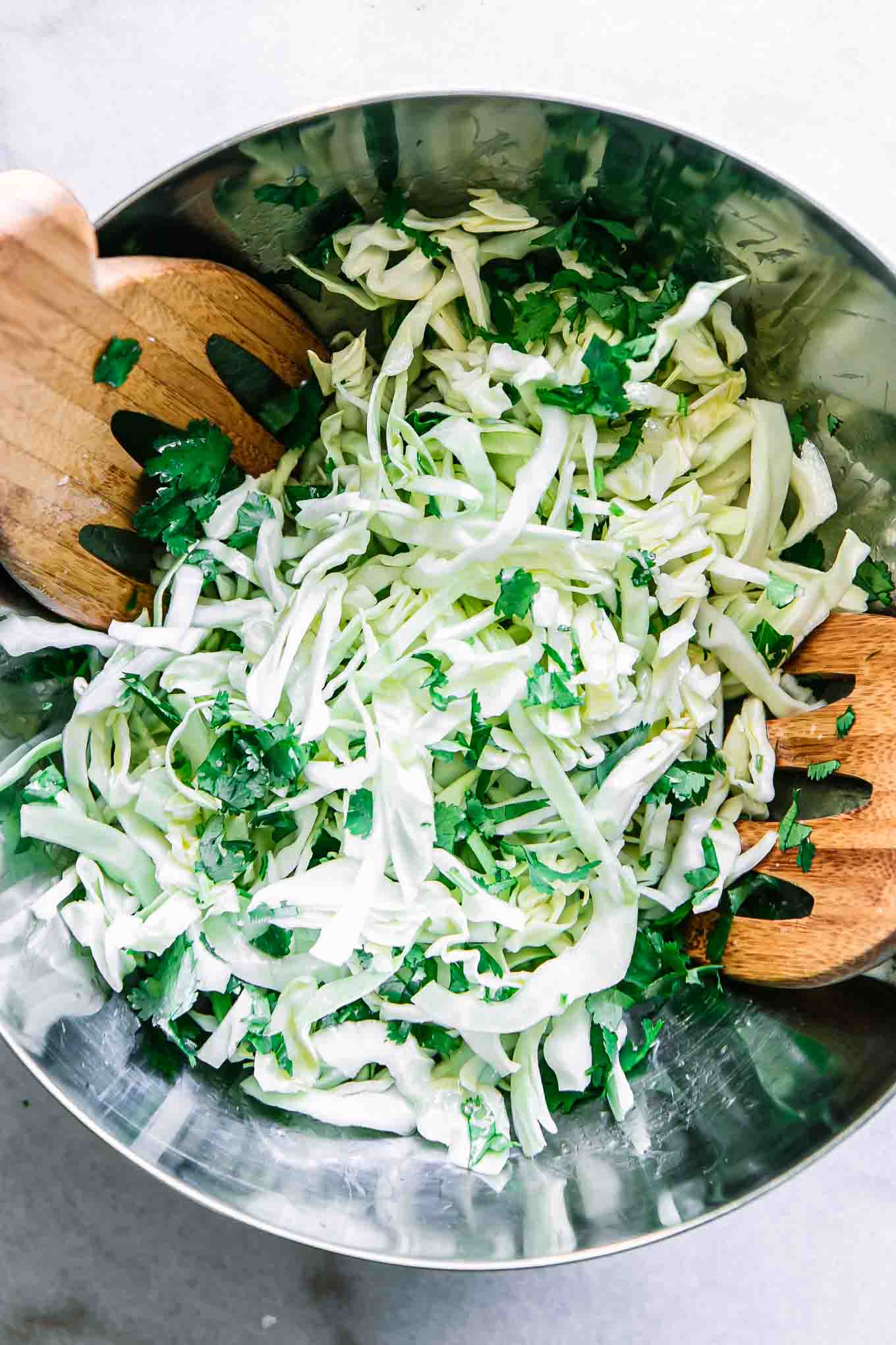 sliced cabbage, chopped cilantro, and dressing tossed in a large mixing bowl