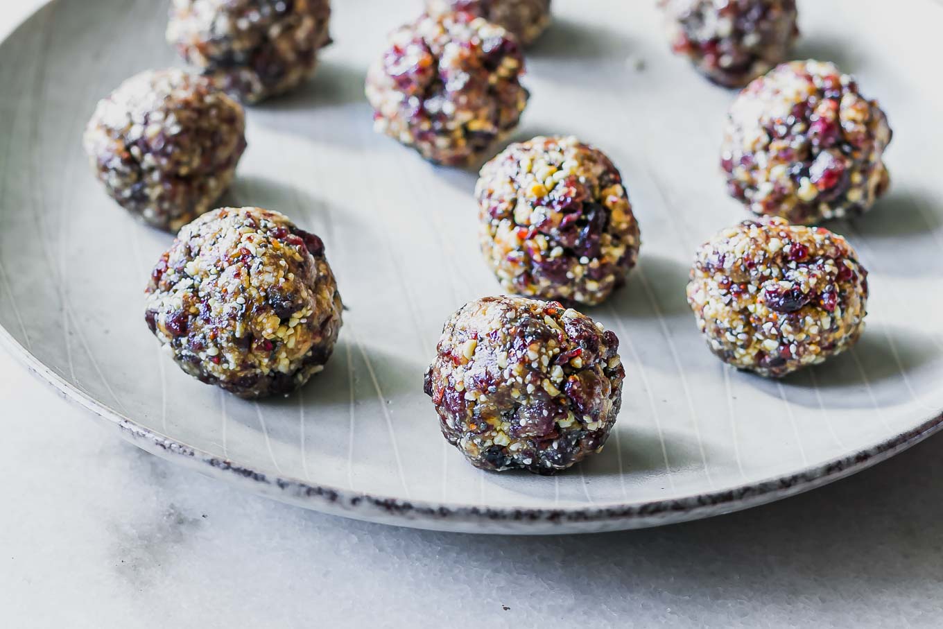 small cranberry bliss snack balls on a white plate on a white table