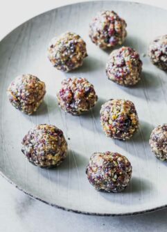 small cranberry and nut snack balls on a white plate on a white table