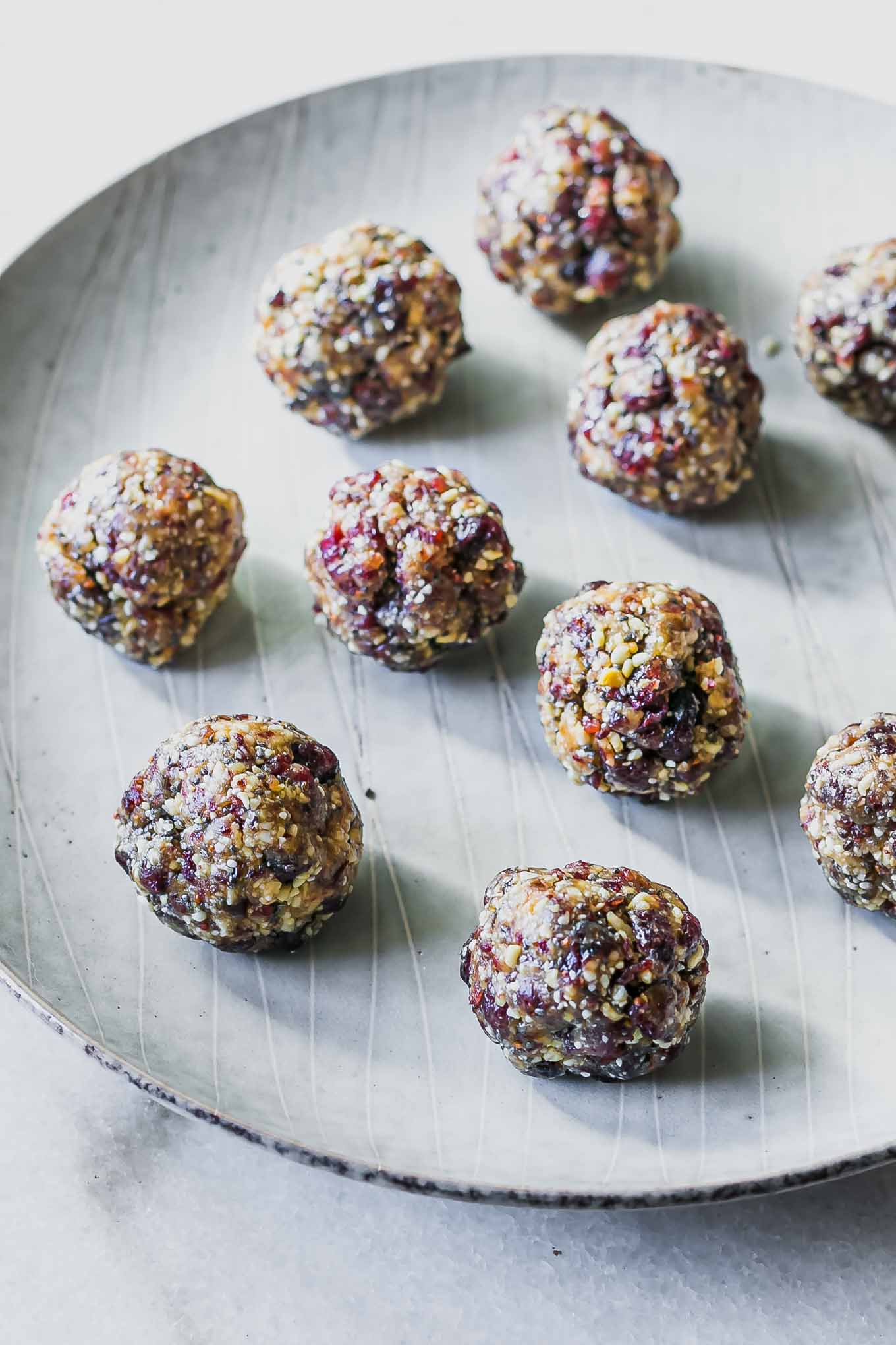 small cranberry and nut snack balls on a white plate on a white table