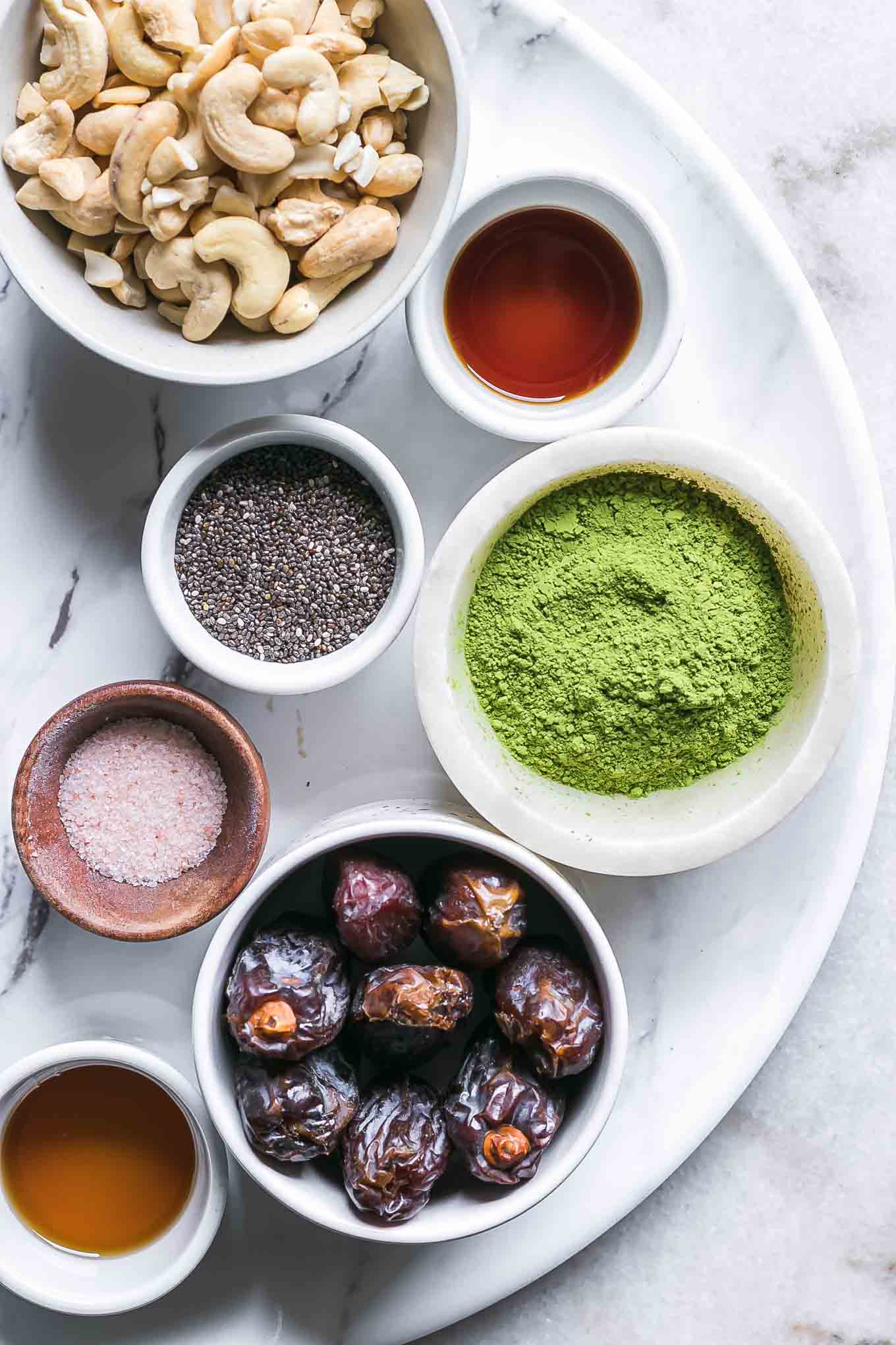 bowls of matcha powder, cashews, dates, maple syrup, chia seeds, vanilla extract, and salt for energy balls