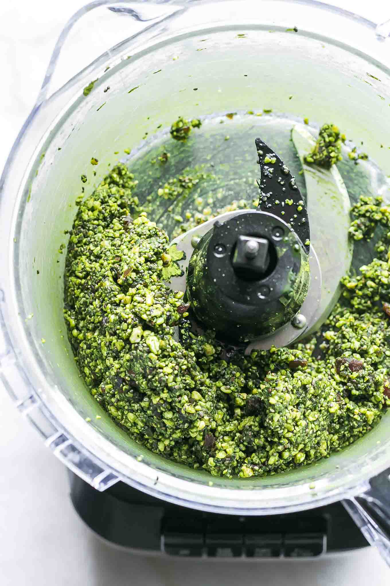 a food processor with blended green matcha energy ball ingredients