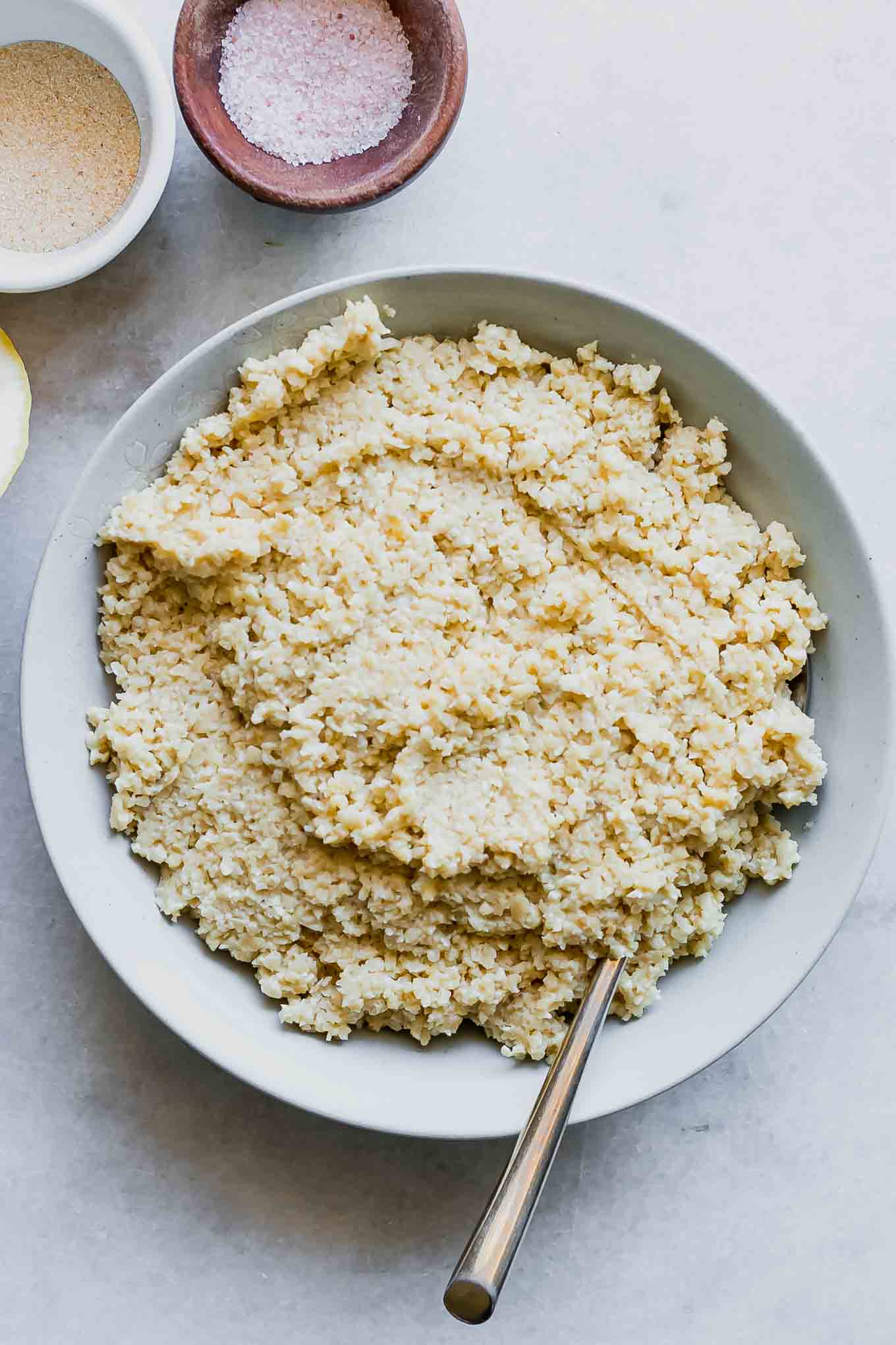 a bowl of vegan cashew ricotta cheese with a gold fork on a white table