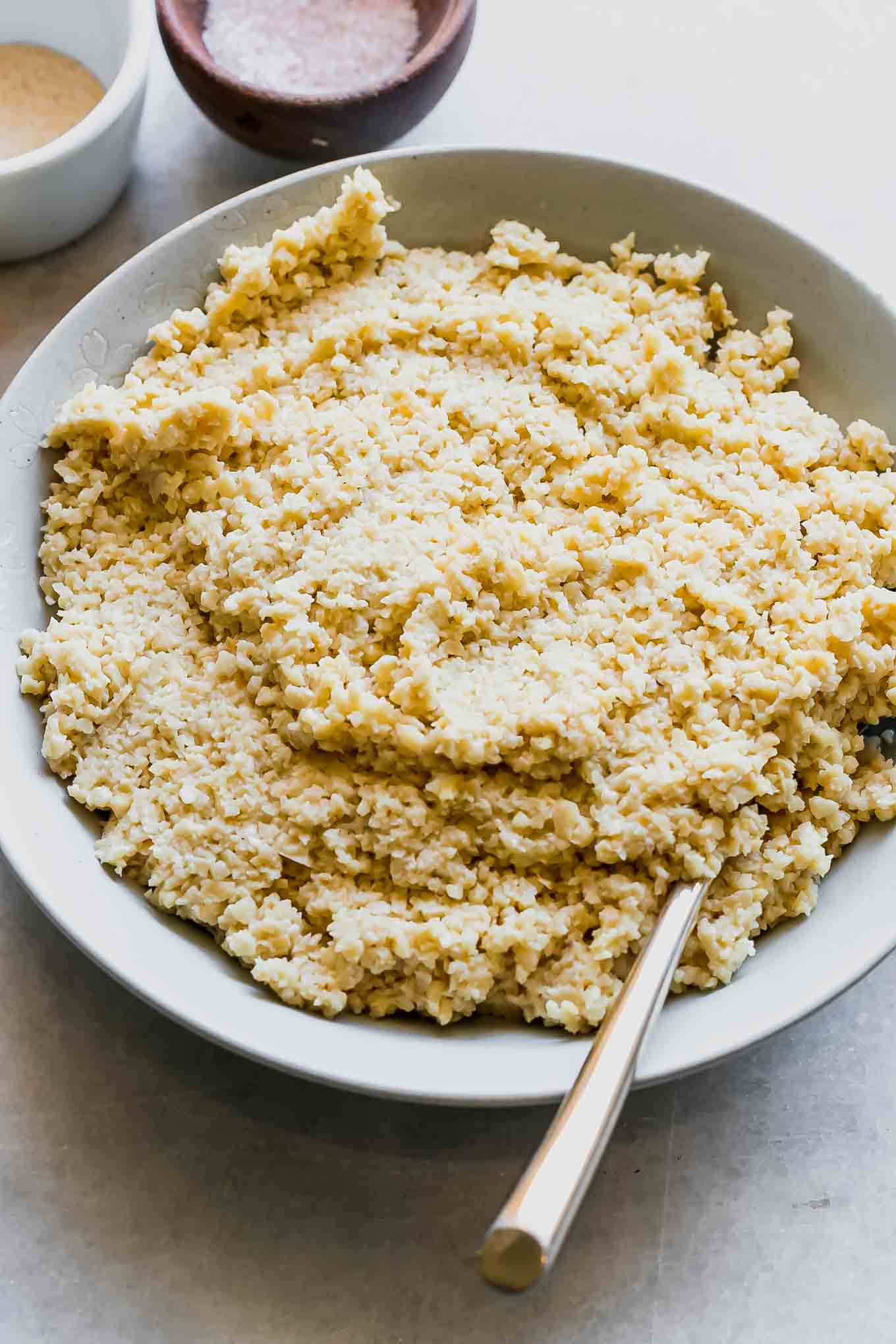 a bowl of vegan cashew ricotta on a white table with bowls of spices