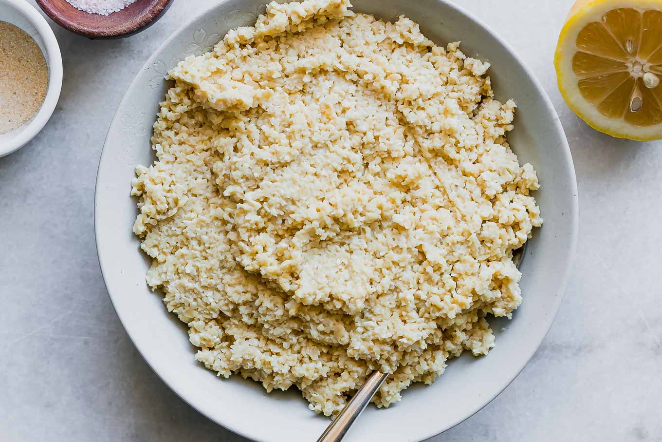 a close up photo of vegan ricotta cheese in a bowl with spices on a white table