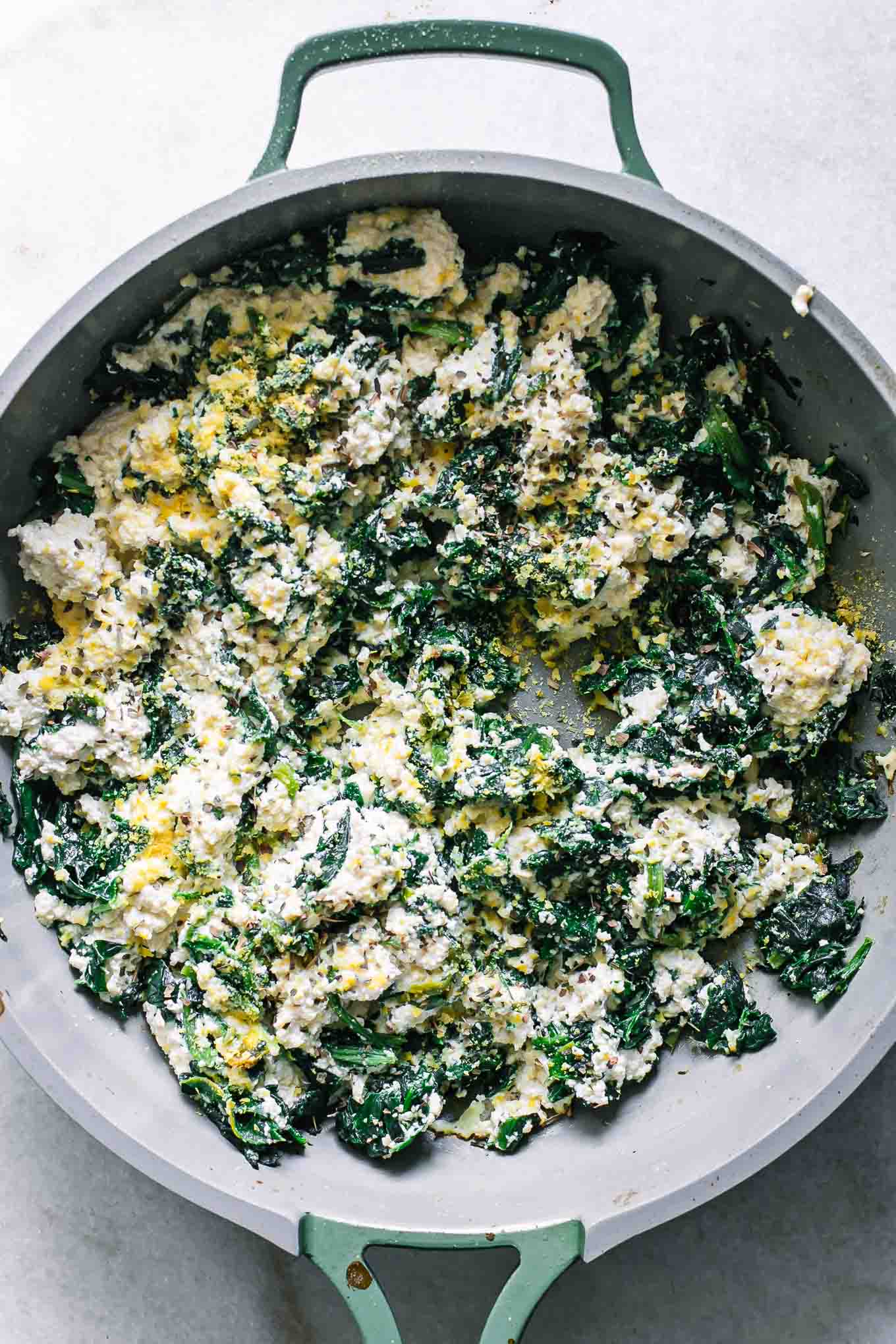 a pan with vegan ricotta cheese and spinach for stuffed shells filling