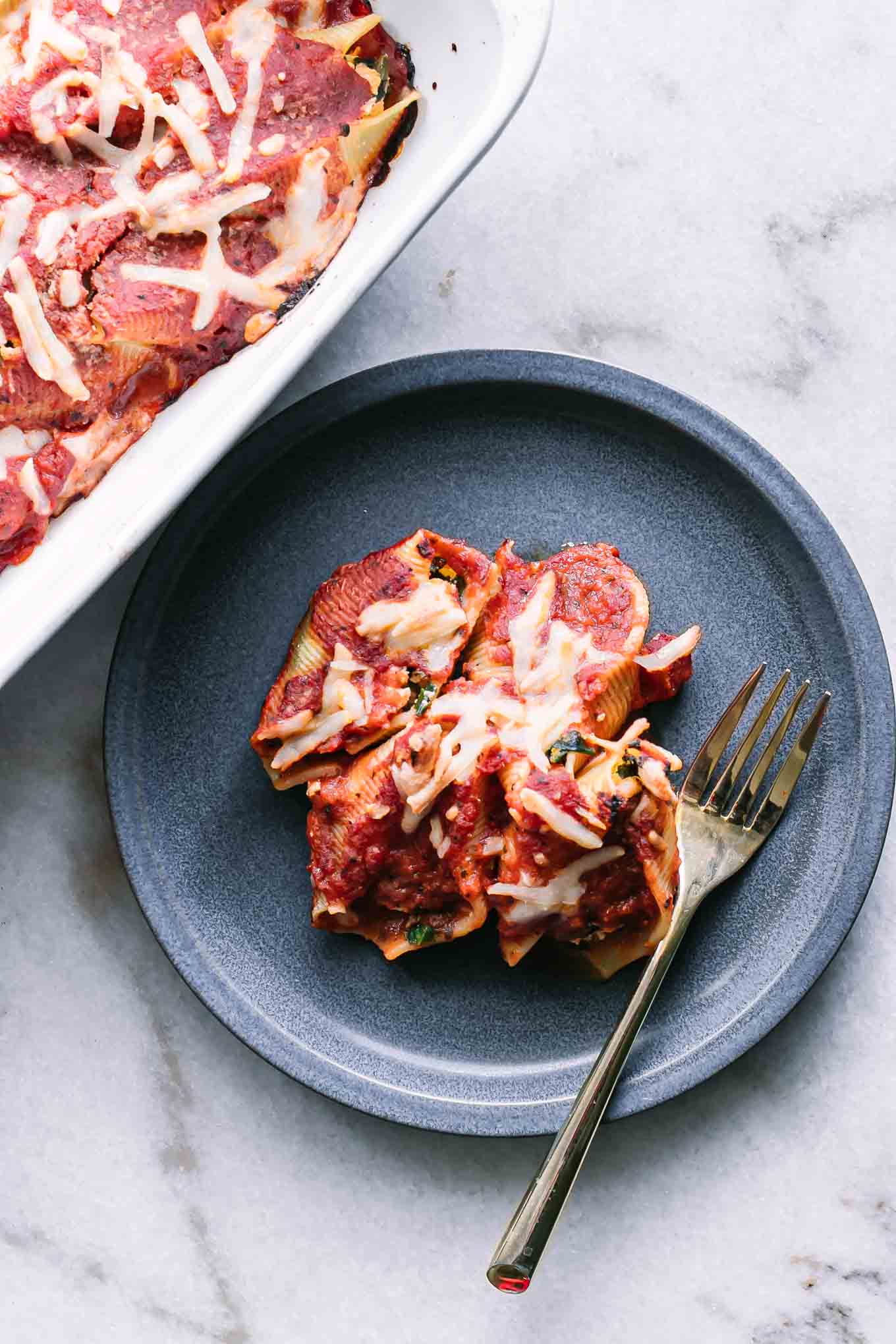 vegan stuffed pasta shells on a blue plate with a gold fork