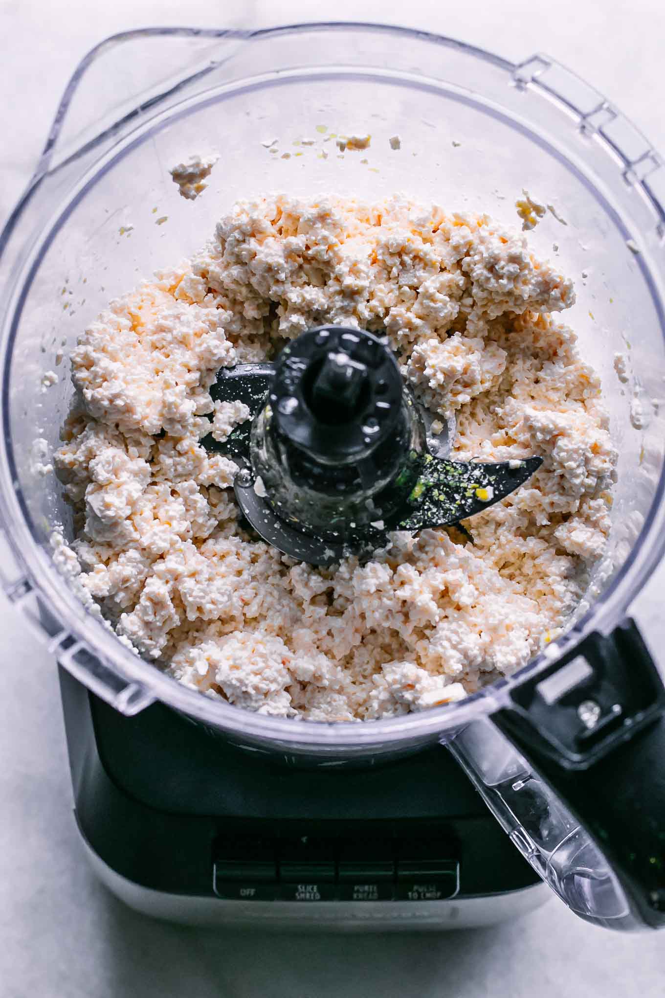 a food processor with blended tofu ricotta cheese inside