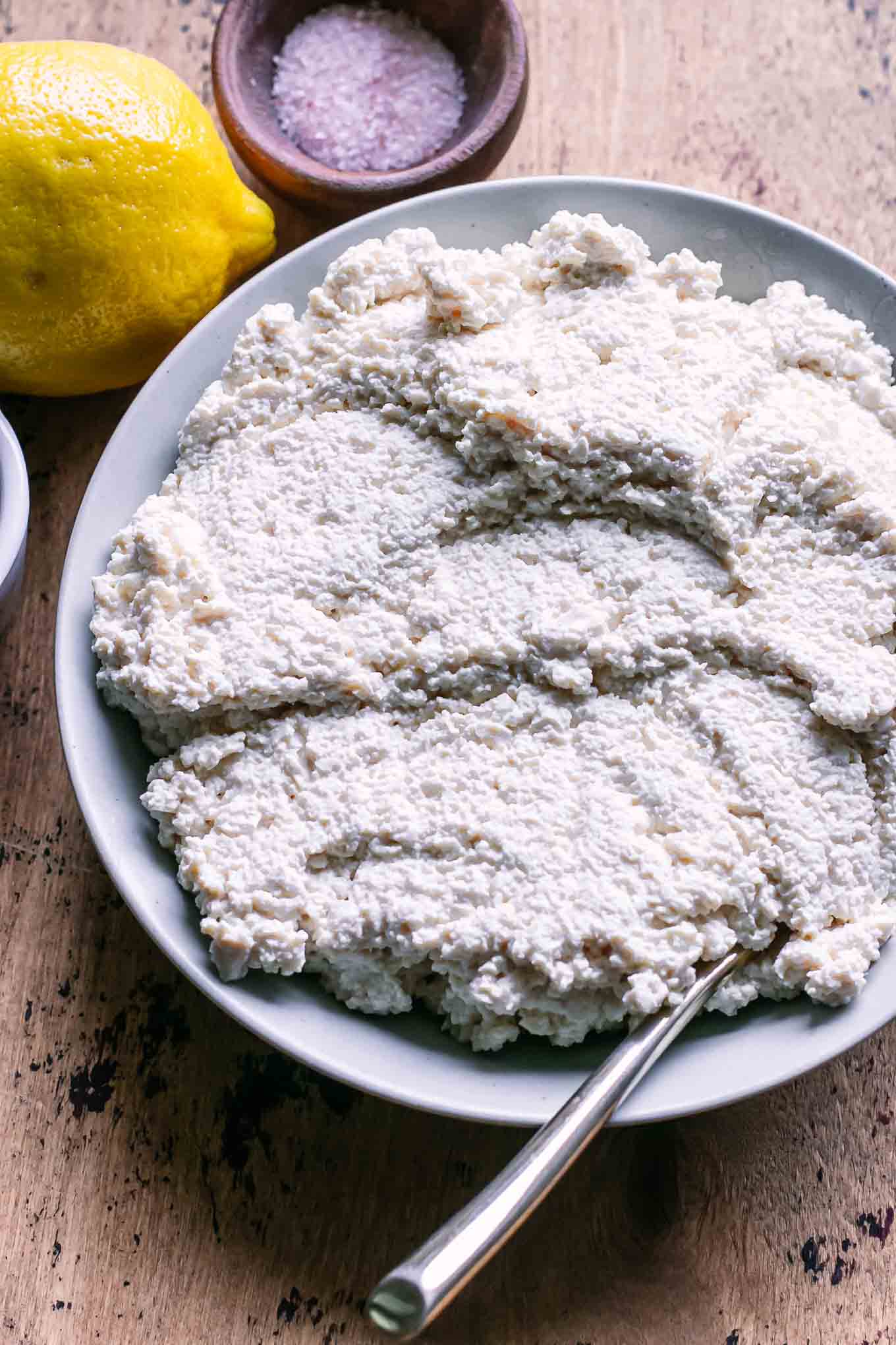 a bowl of vegan ricotta cheese with tofu on a wood table