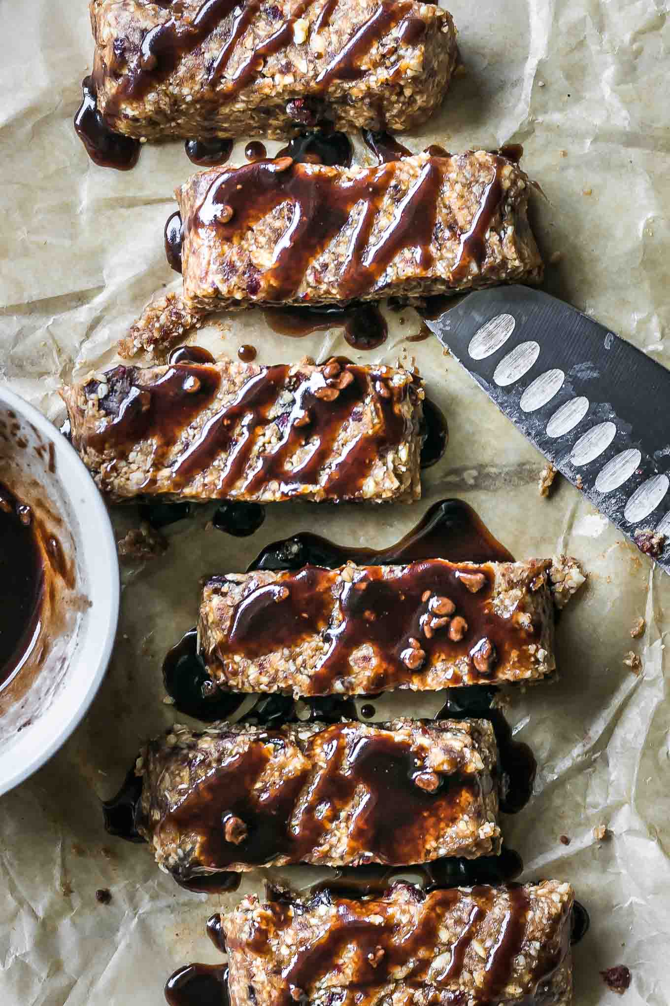 homemade peanut butter granola bars with chocolate drizzled on top on parchment paper